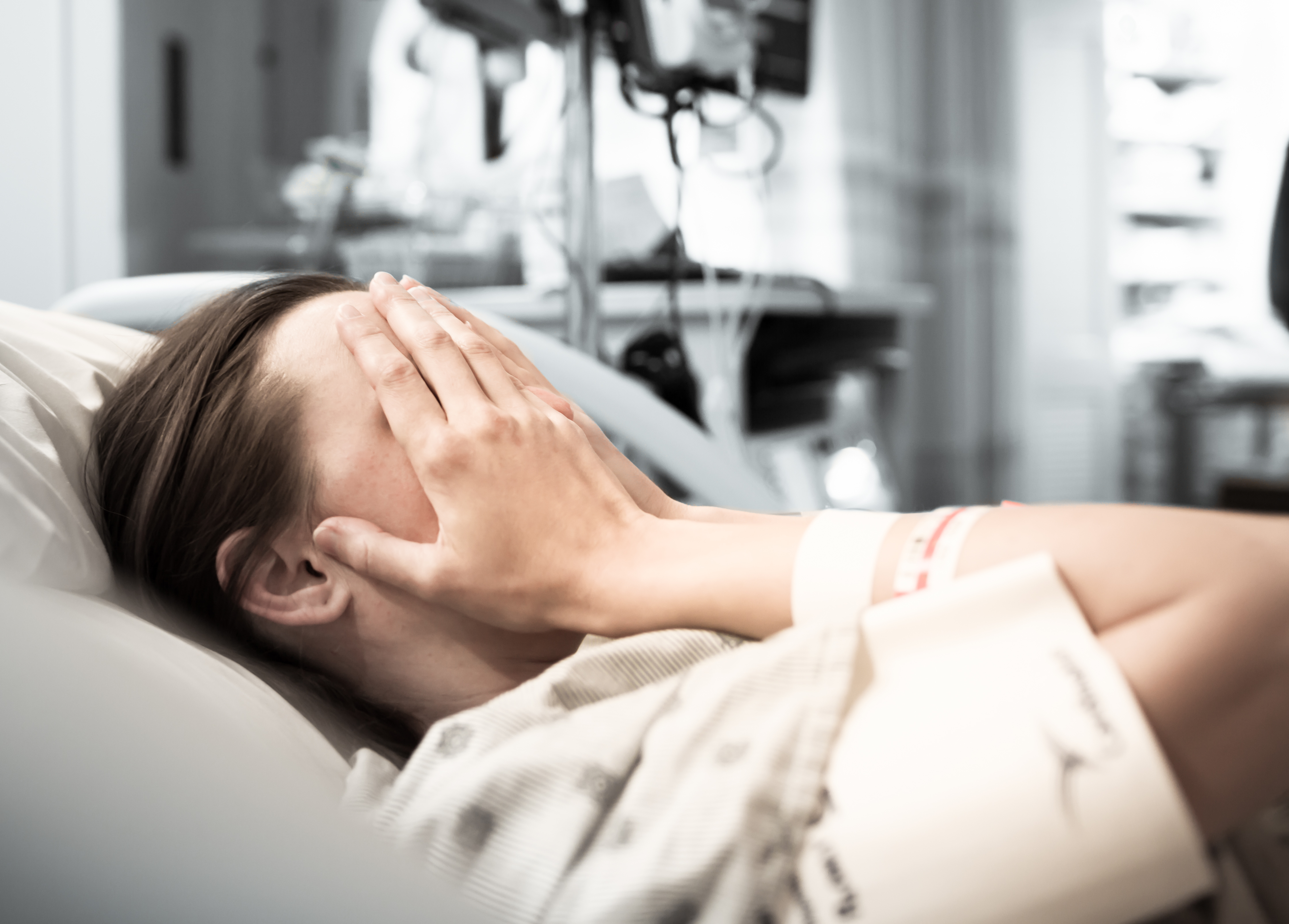 Mujer joven paciente tumbada en la cama de un hospital | Fuente: Shutterstock