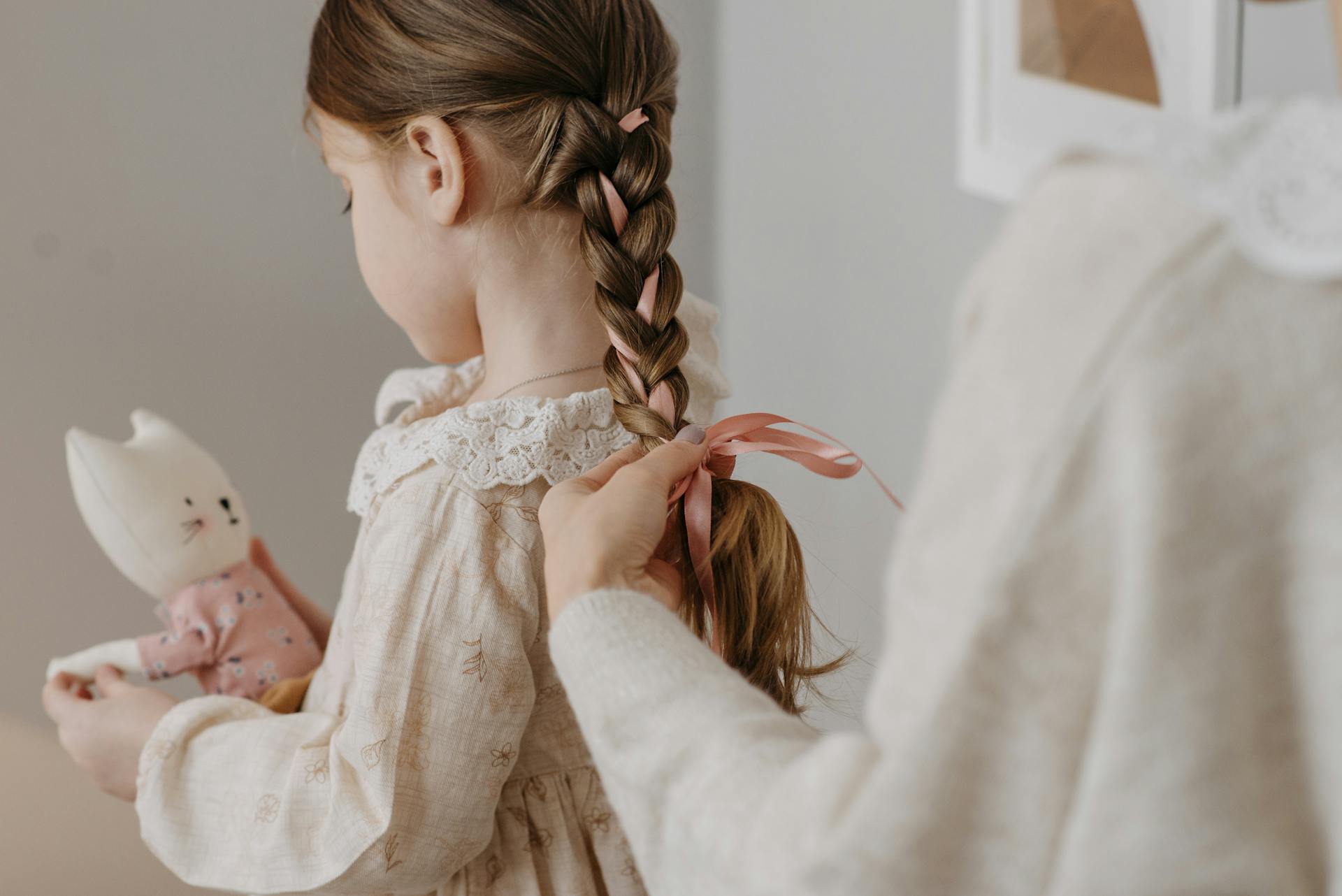 Une femme qui attache un ruban sur les cheveux de sa fille | Source : Pexels