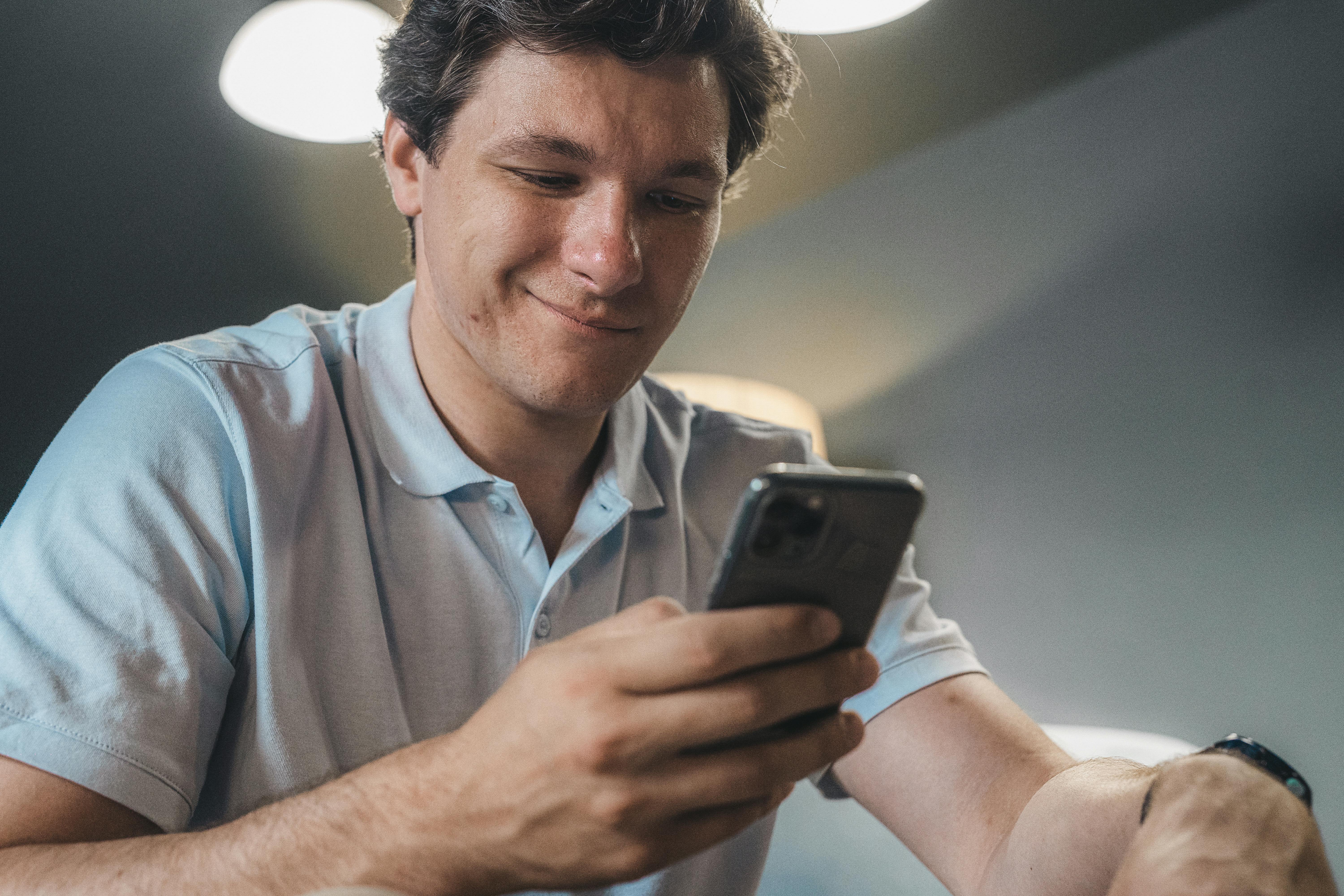 Un homme heureux utilisant son téléphone | Source : Pexels