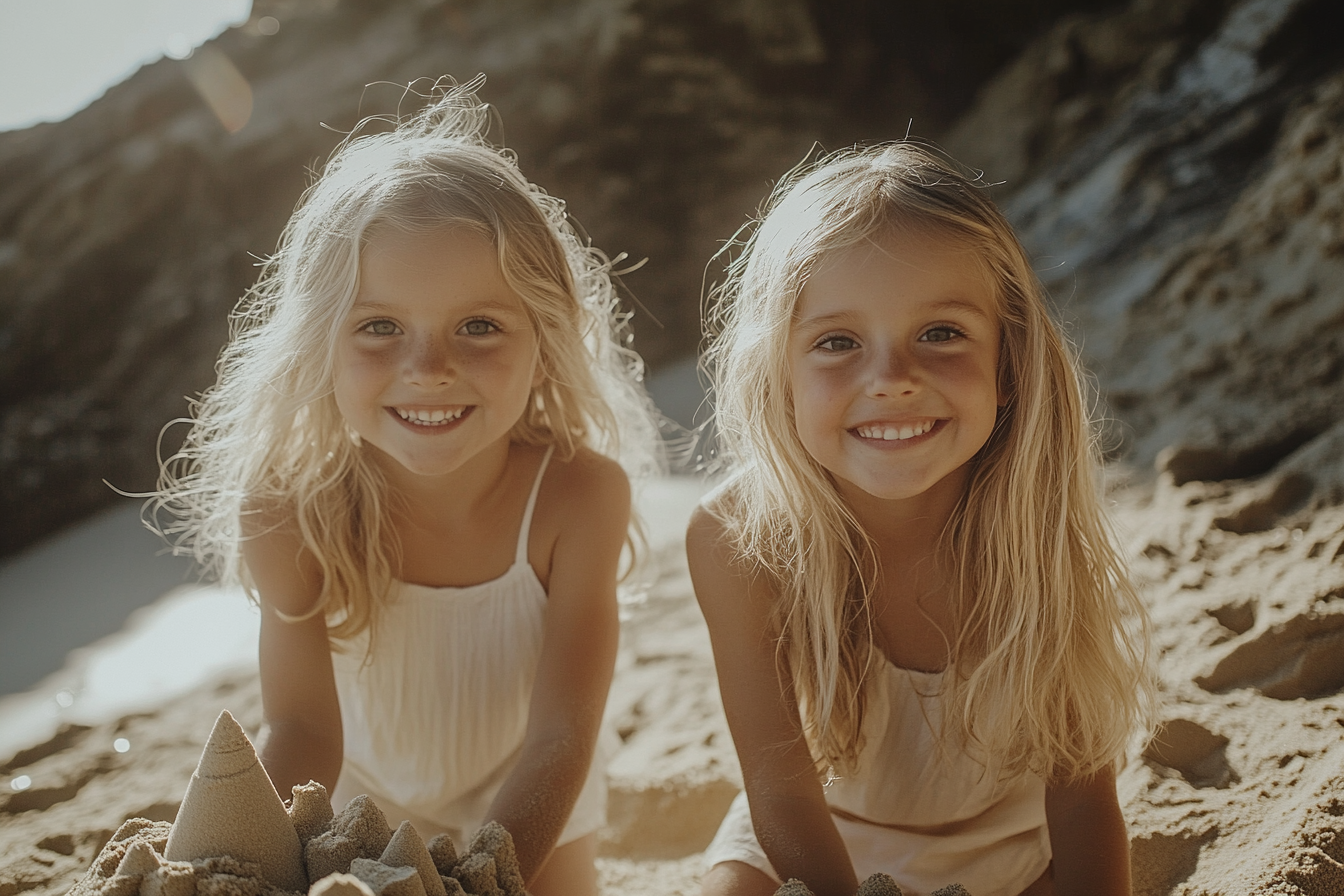 Deux fillettes blondes, âgées de 5 ans, sourient et construisent un château de sable sur la plage | Source : Midjourney