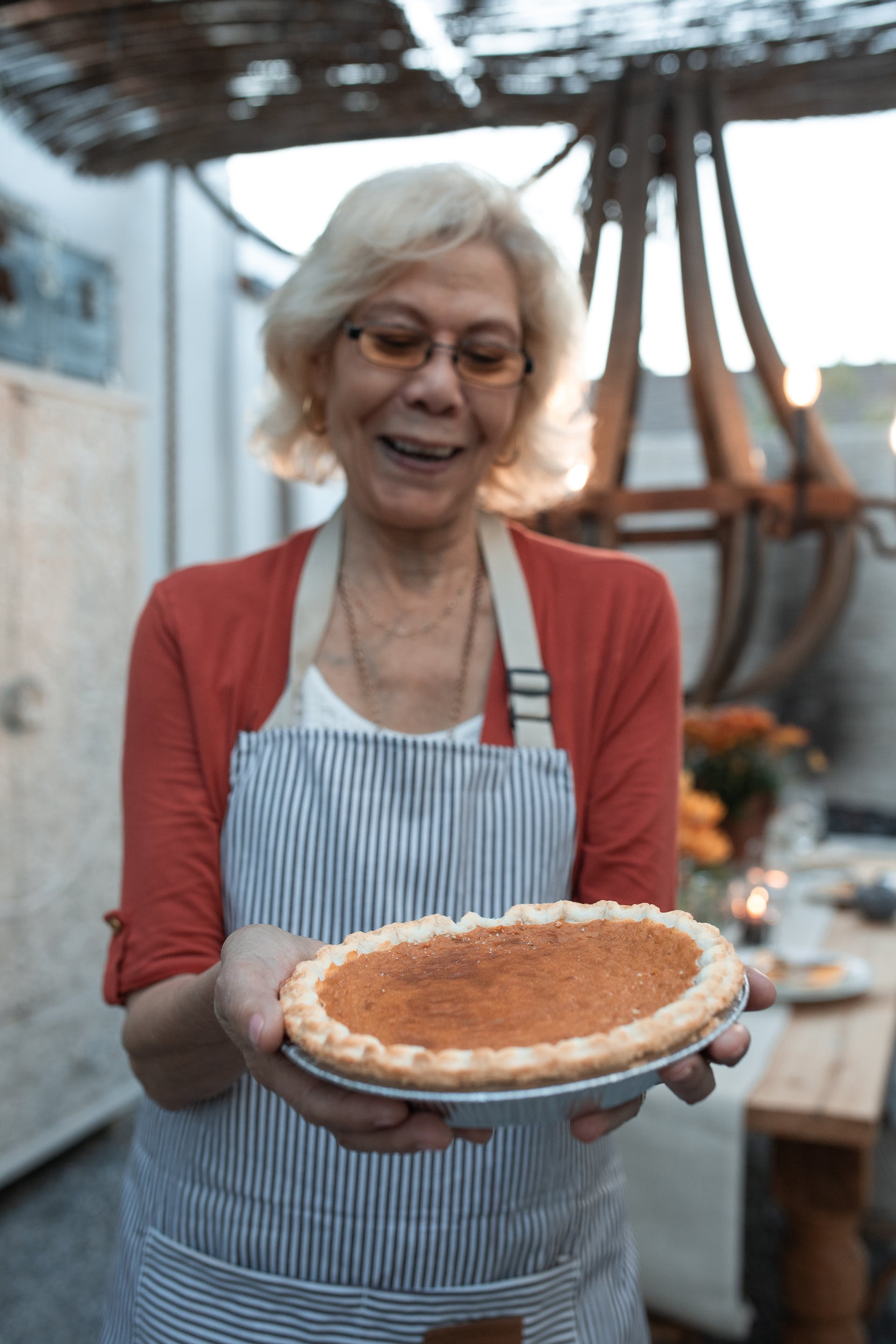Une femme âgée souriante tenant une tarte à la citrouille | Source : Pexels
