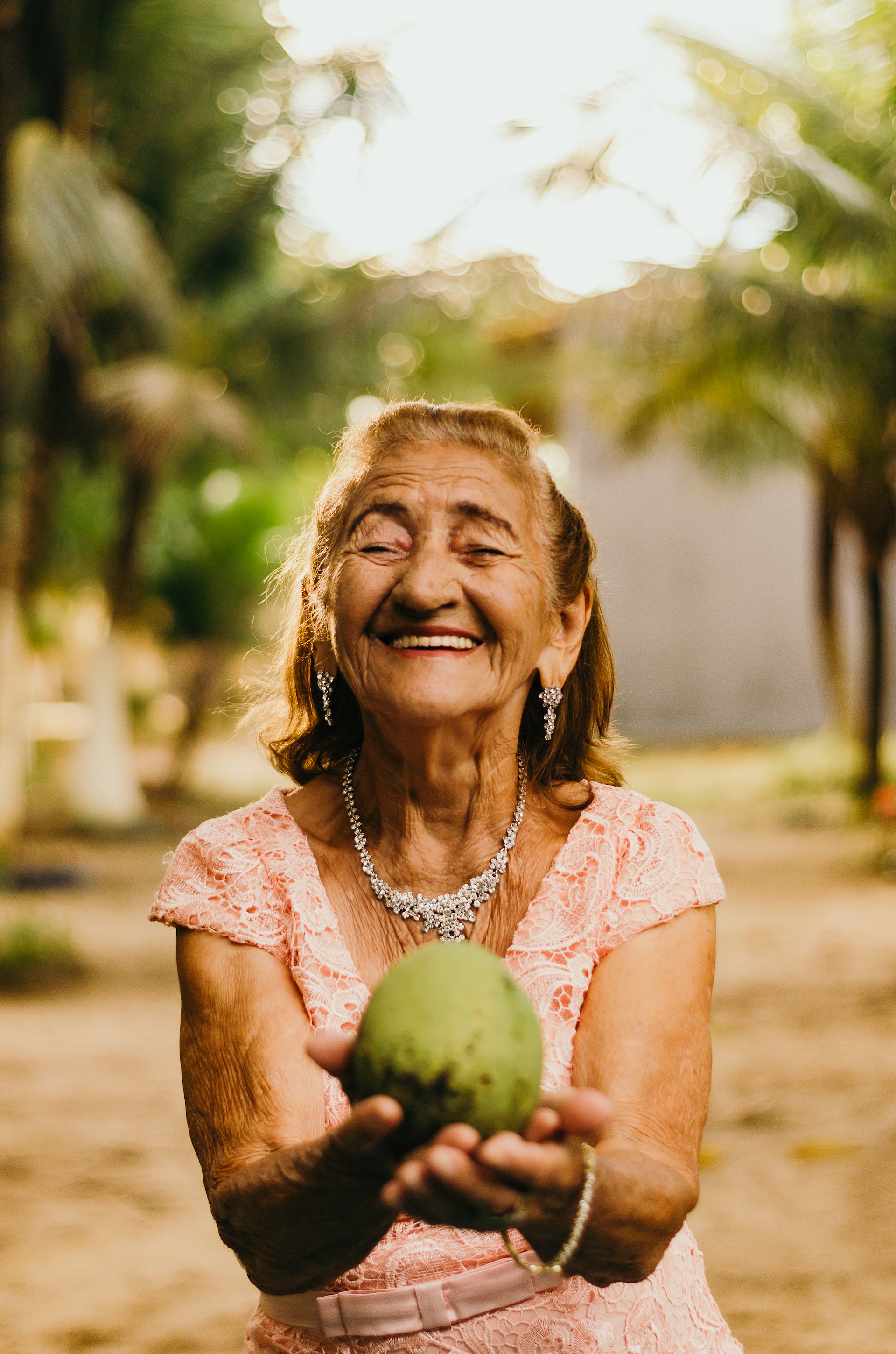 Vieille femme souriant et tenant une noix de coco | Source : Pexels