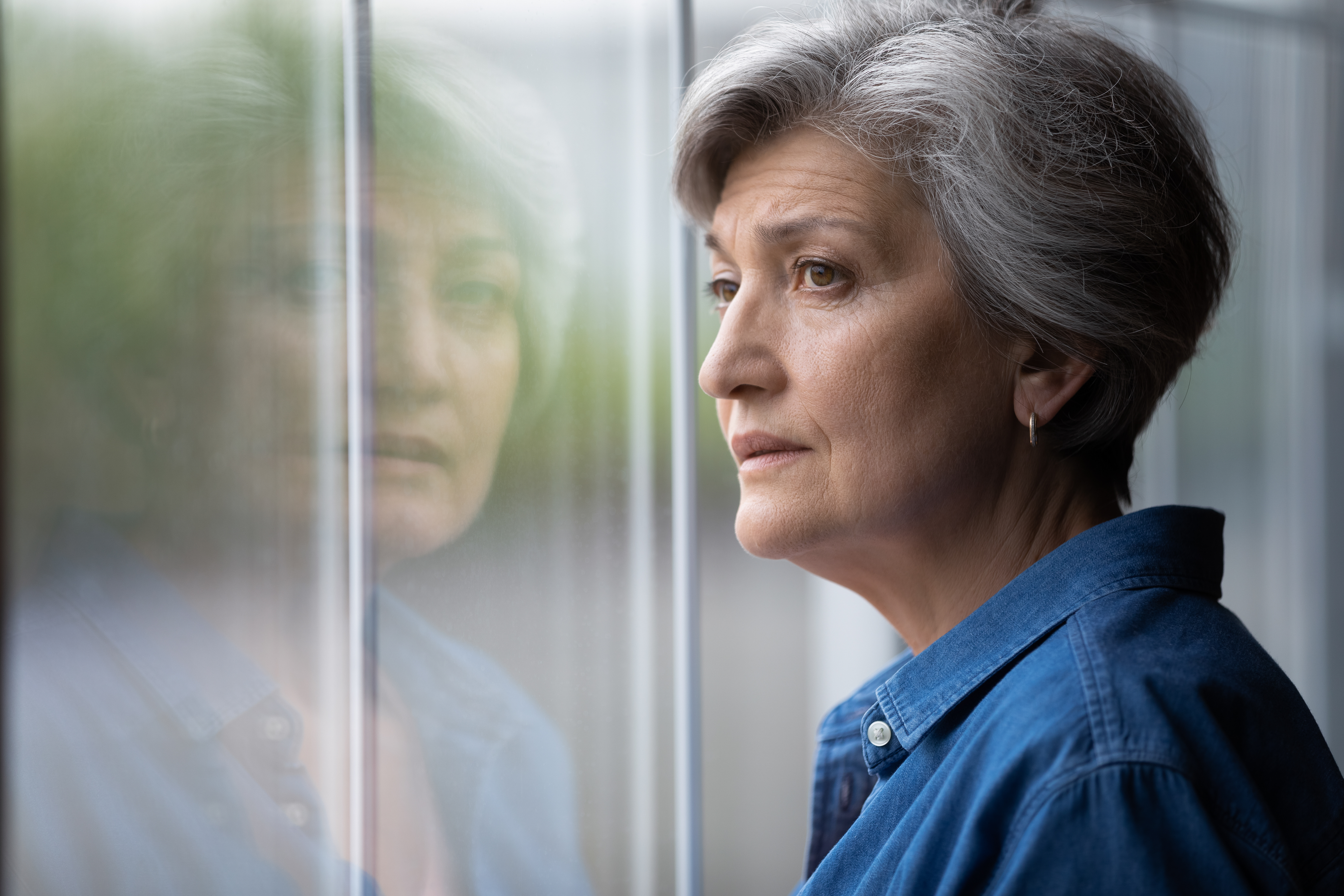Une femme âgée contrariée qui regarde dehors | Source : Shutterstock