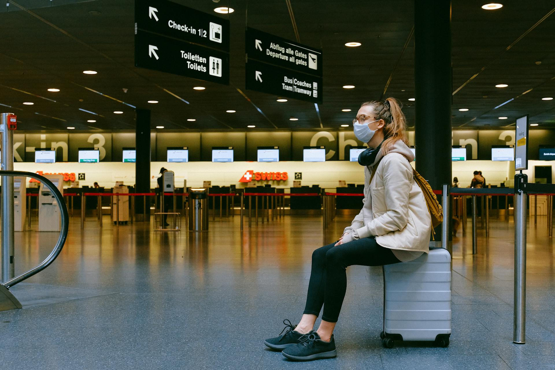 Une femme assise sur une valise dans un aéroport | Source : Pexels