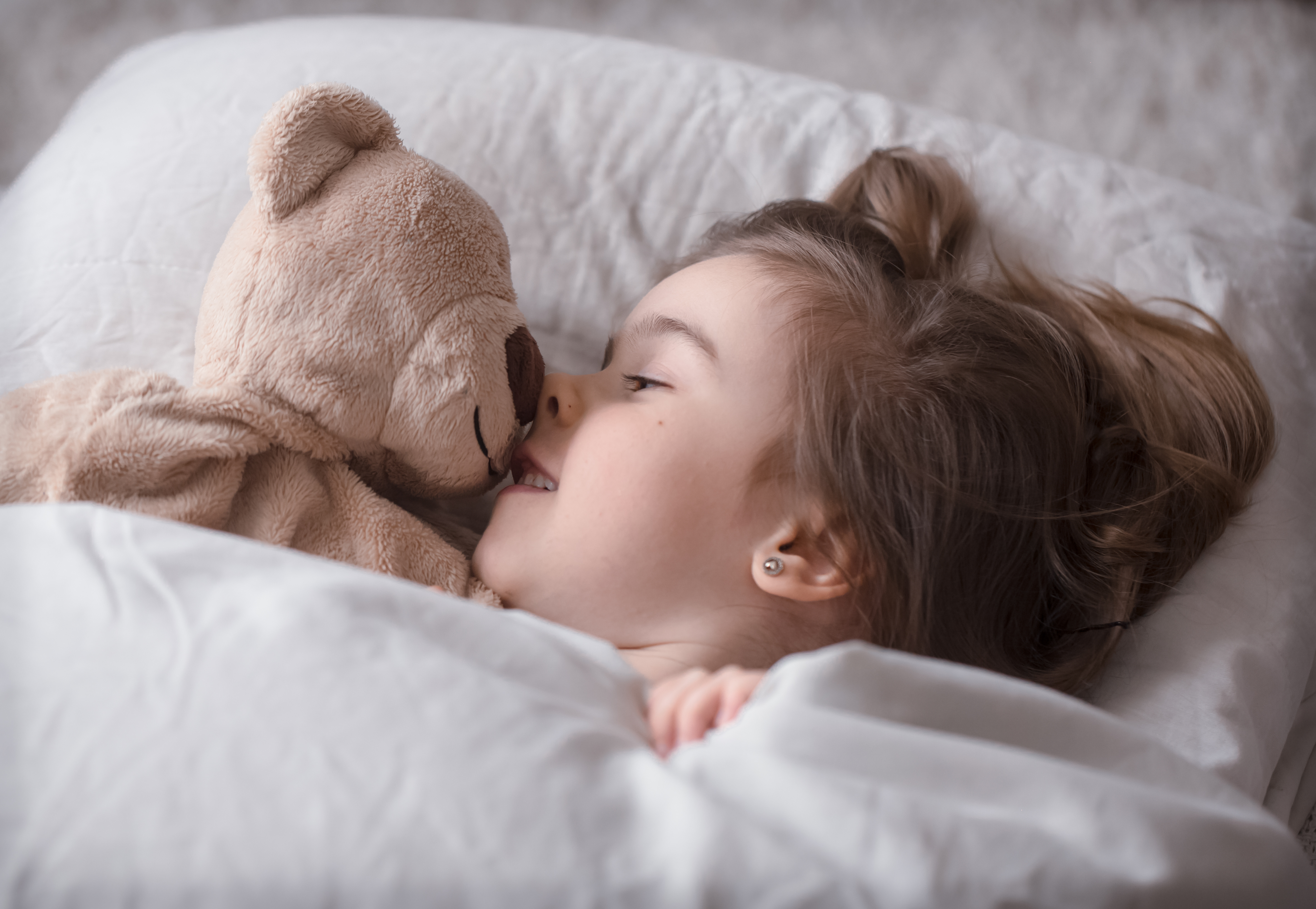 Une fille souriante dans son lit | Source : Freepik