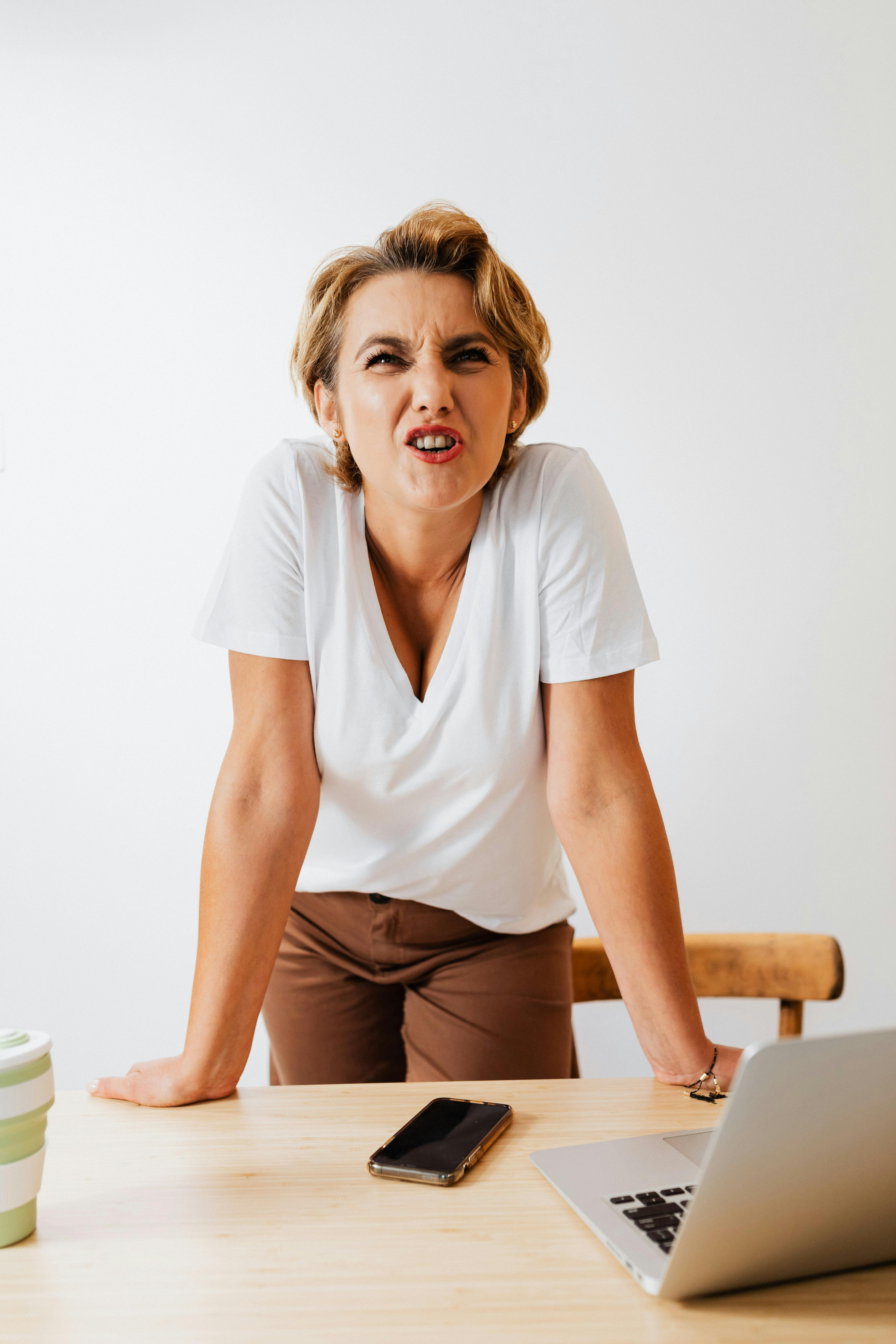 Une femme réagissant avec colère tout en posant ses mains sur une table | Source : Pexels