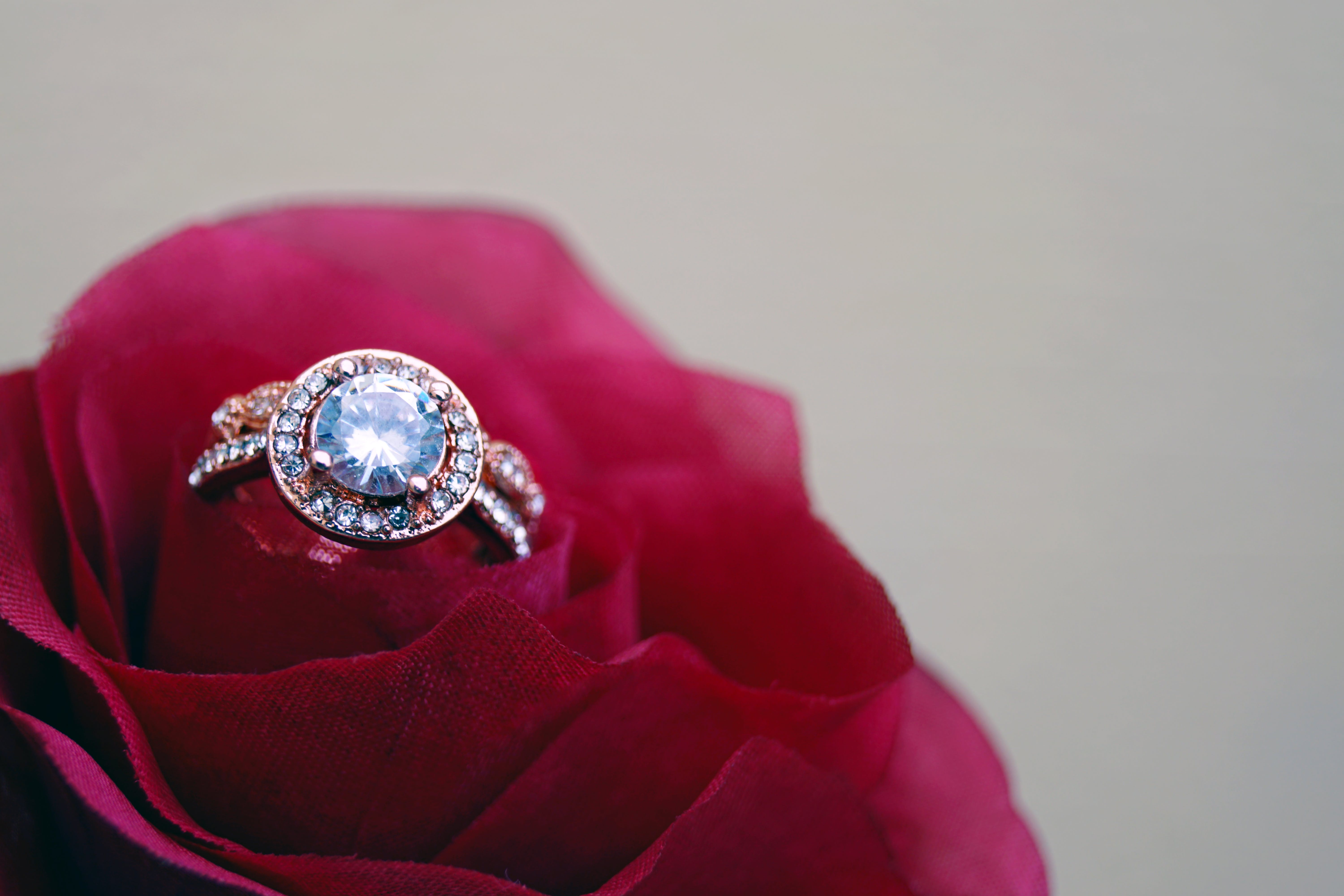 Gros plan d'un anneau en forme de grappe, de couleur or, sur une rose : Pexels