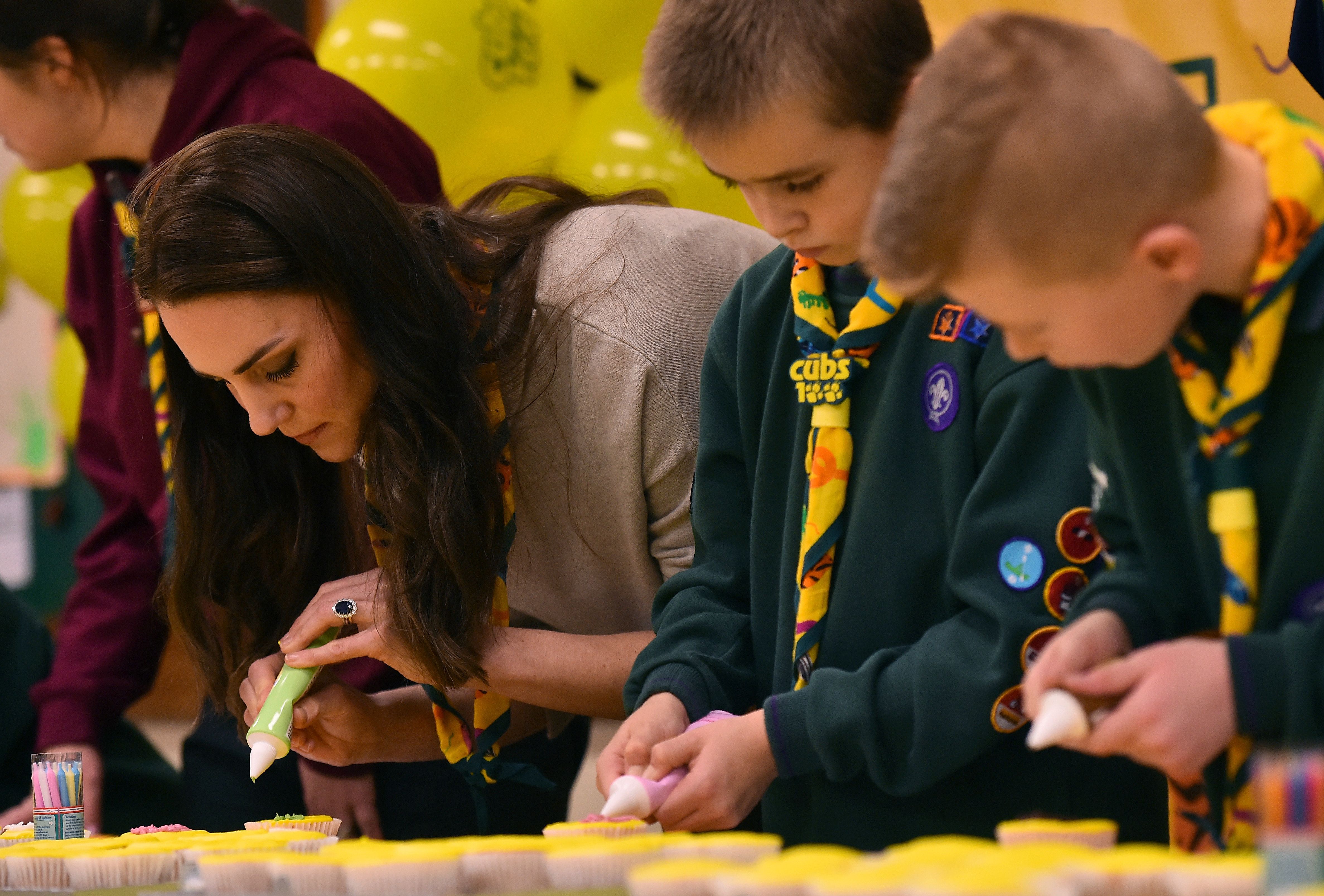 Kate Middleton glace un cupcake avec des membres de la meute des louveteaux lors d'une réunion de la meute des louveteaux à Kings Lynn, dans l'est de l'Angleterre, le 14 décembre 2016 | Source : Getty Images
