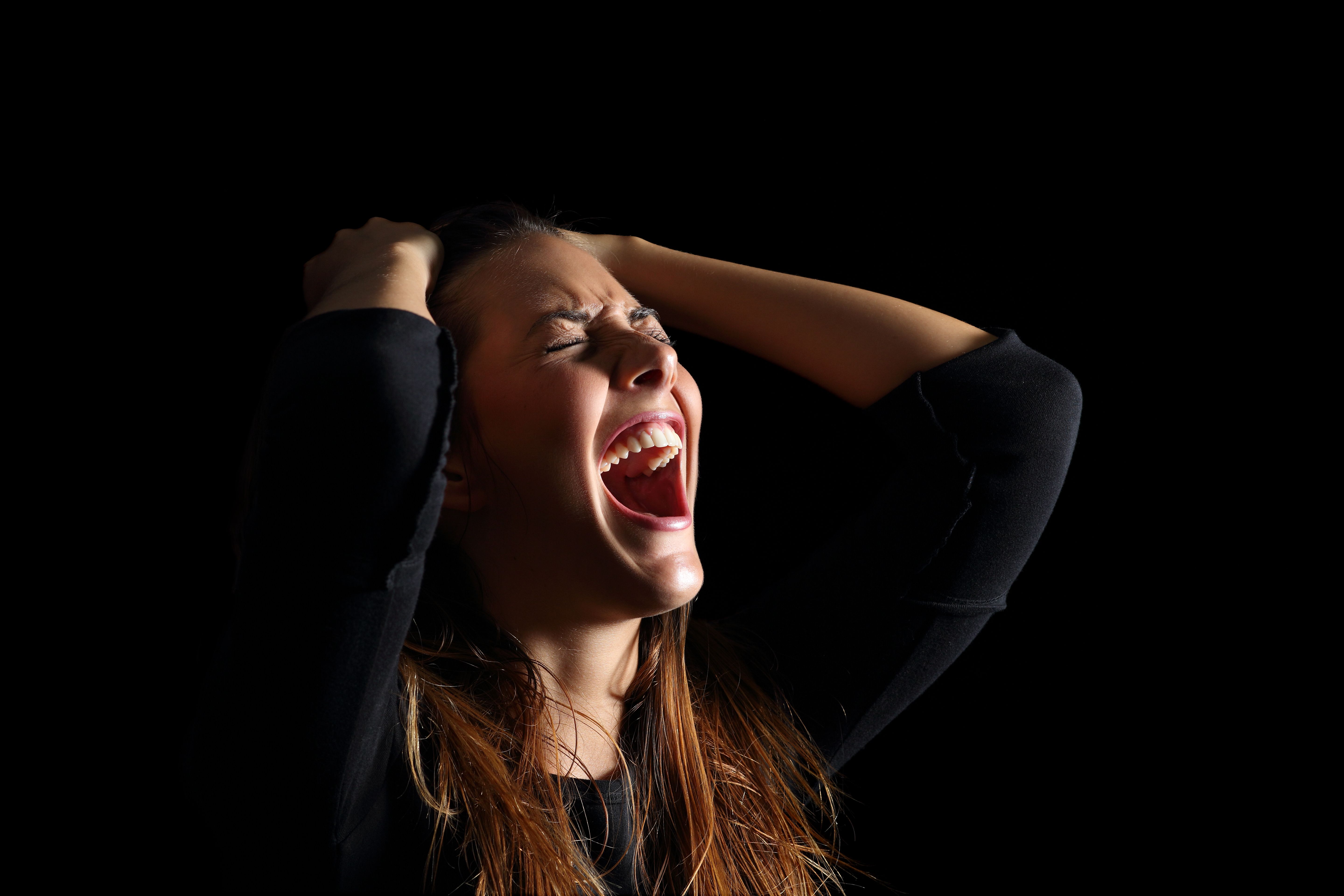 Une femme qui a les yeux fermés et qui crie en se tenant les cheveux | Source : Getty Images