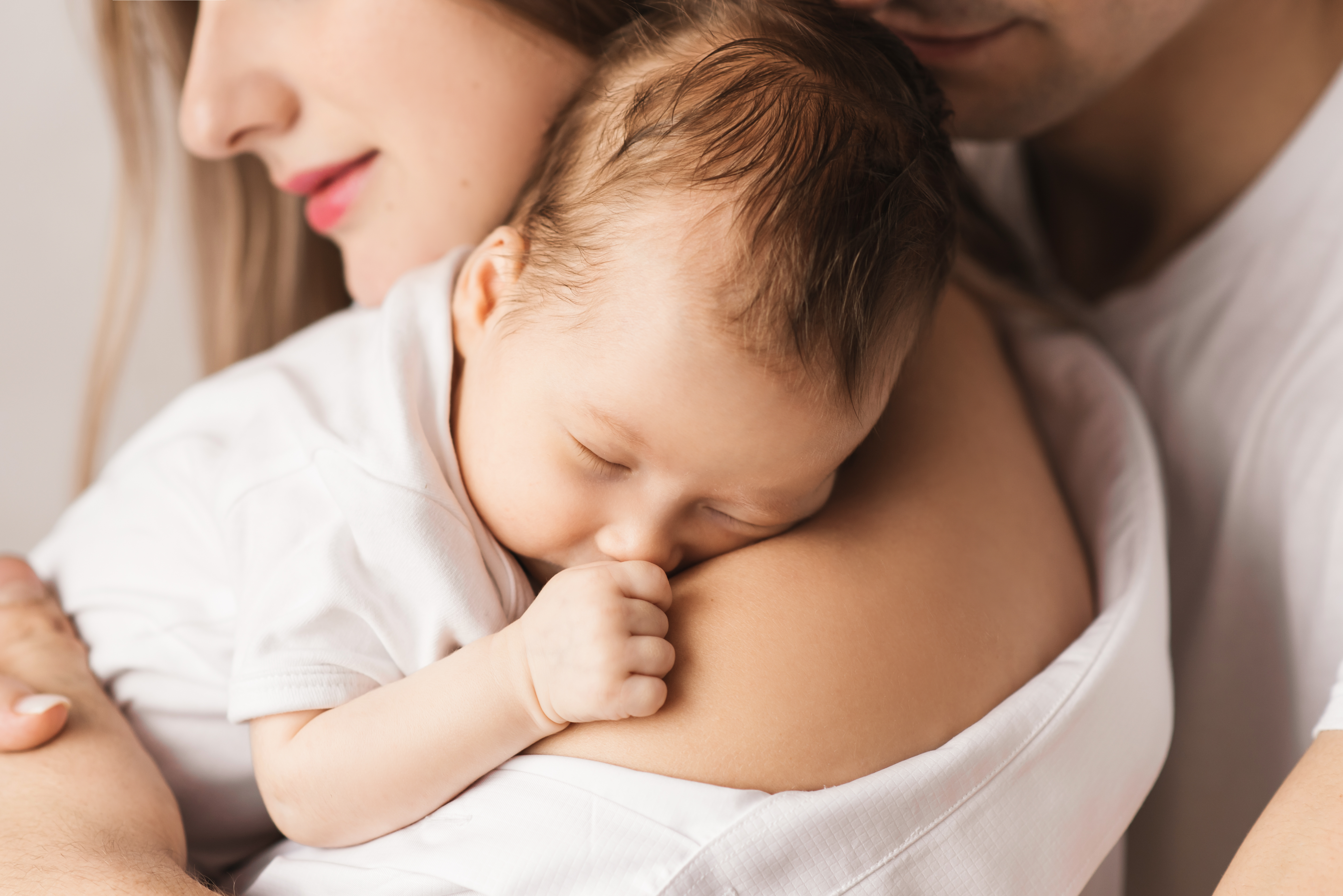Une mère tenant son nouveau-né avec son mari derrière elle | Source : Shutterstock