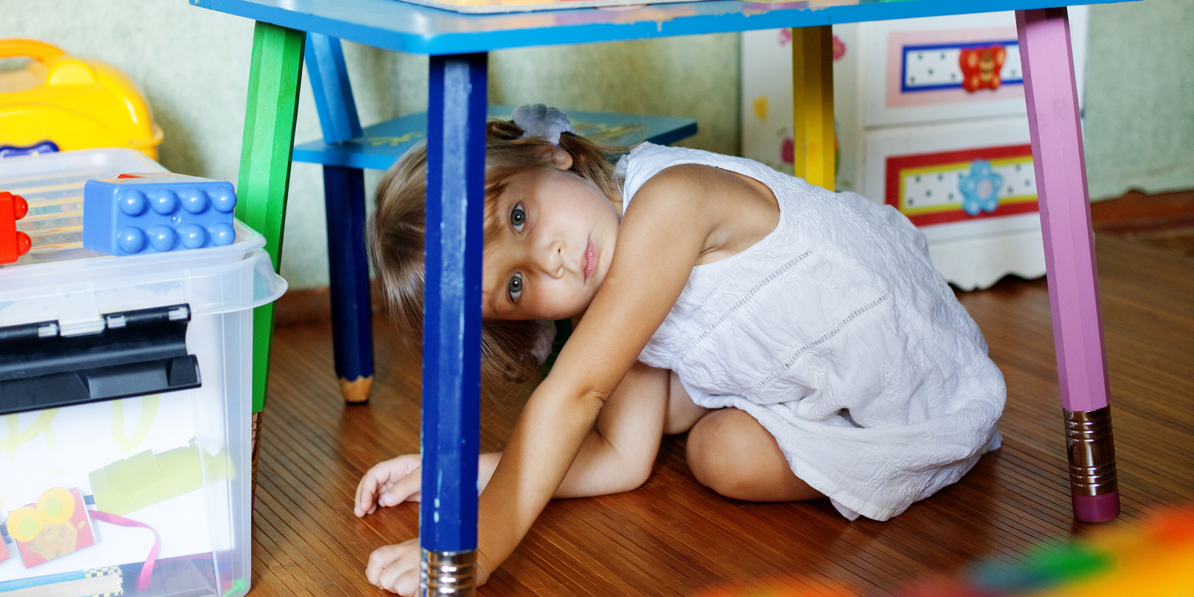 Une enfant qui se cache sous une table | Source : Shutterstock