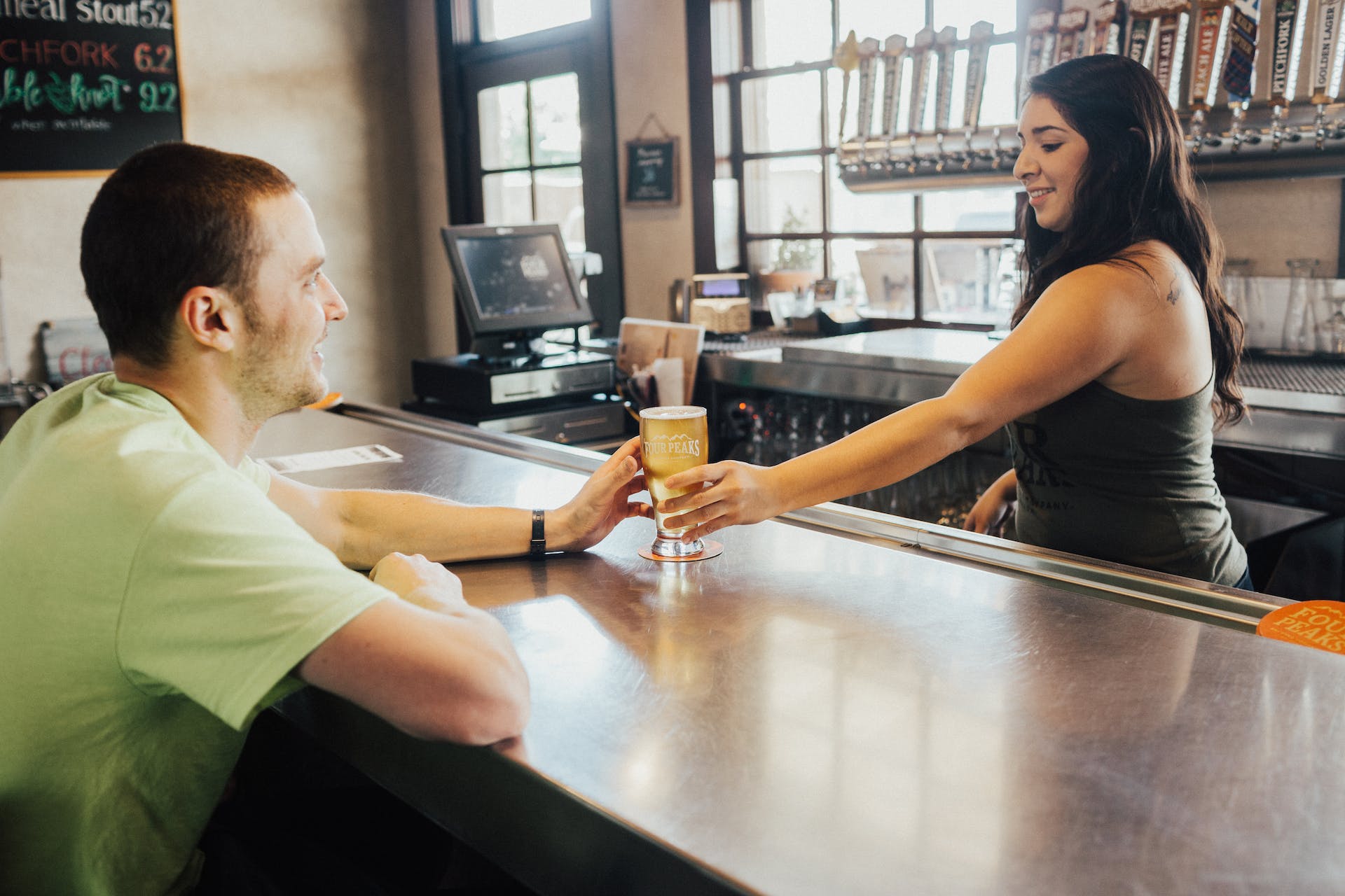 Une barmaid tend un verre de boisson à un client masculin | Source : Pexels