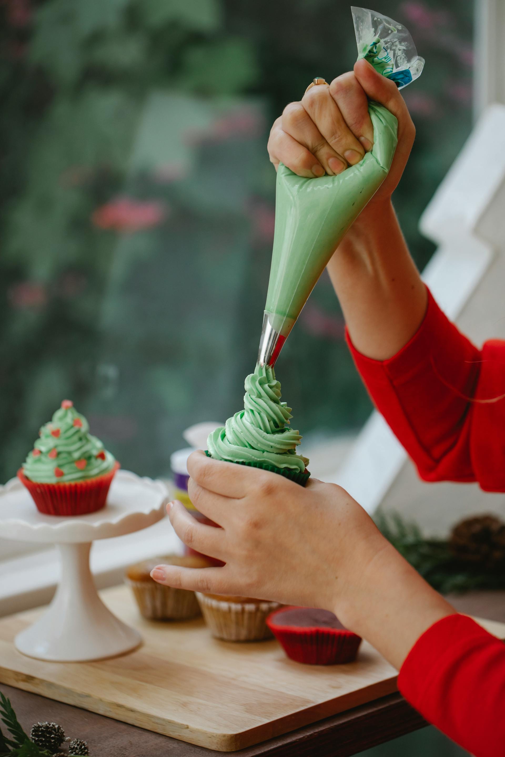 Gros plan d'une femme décorant un cupcake maison avec de la crème | Source : Pexels