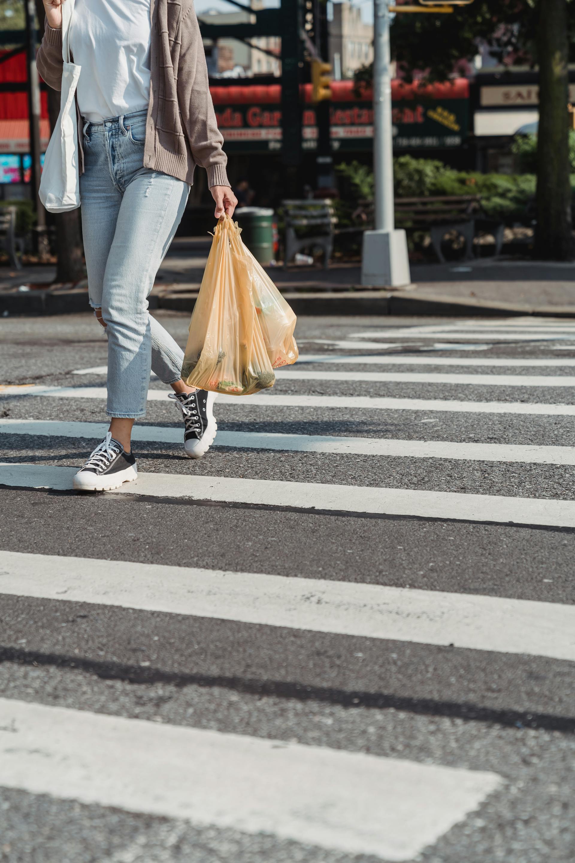 Une femme marchant sur un passage zébré en tenant des sacs d'épicerie | Source : Pexels