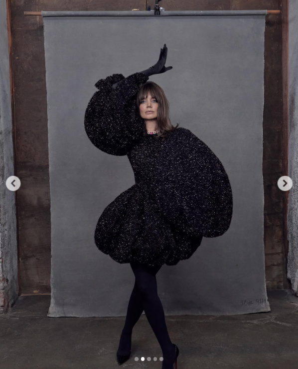 Katie Holmes arbore une robe noire éblouissante avec des gants assortis, et des talons tout en posant sur un fond gris, posté en août 2024 | Source : Instagram/katieholmes