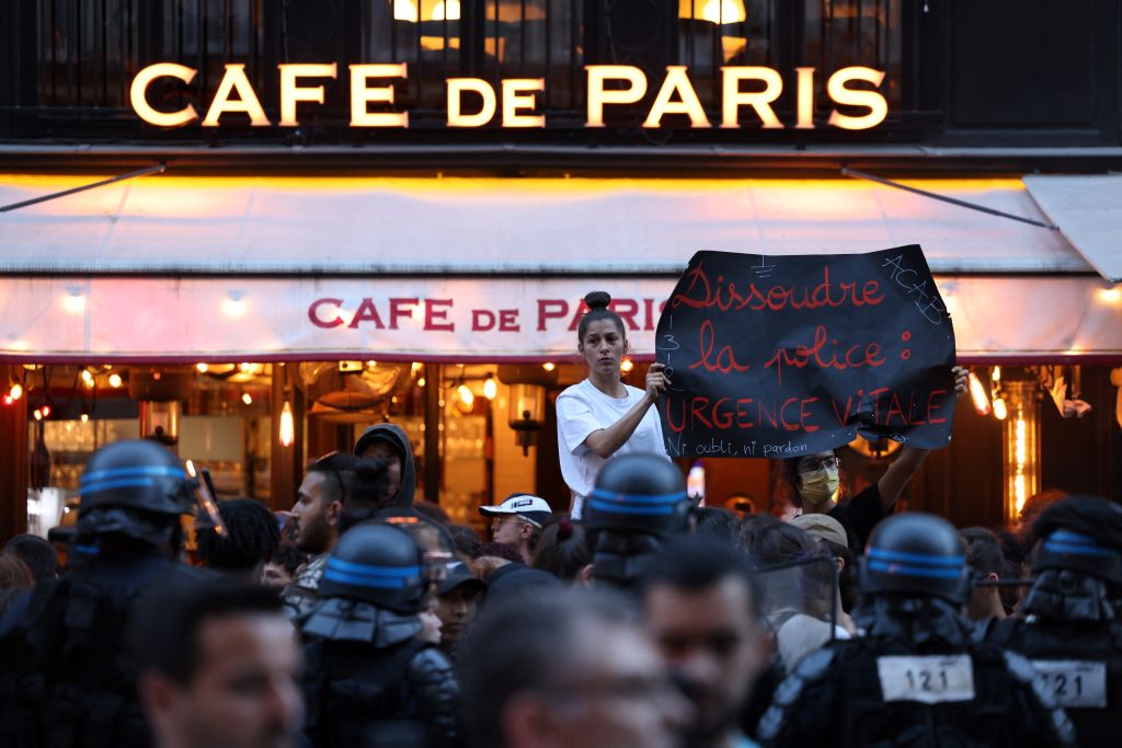 Une manifestante tient une pancarte sur laquelle on peut lire "licencier la police est urgent" lors d'une manifestation à Paris le 30 juin 2023, suite à la mort d'un adolescent abattu par la police française dans une banlieue de Paris le 27 juin.  (Photo by CHARLY TRIBALLEAU / AFP) (Photo by CHARLY TRIBALLEAU/AFP via Getty Images