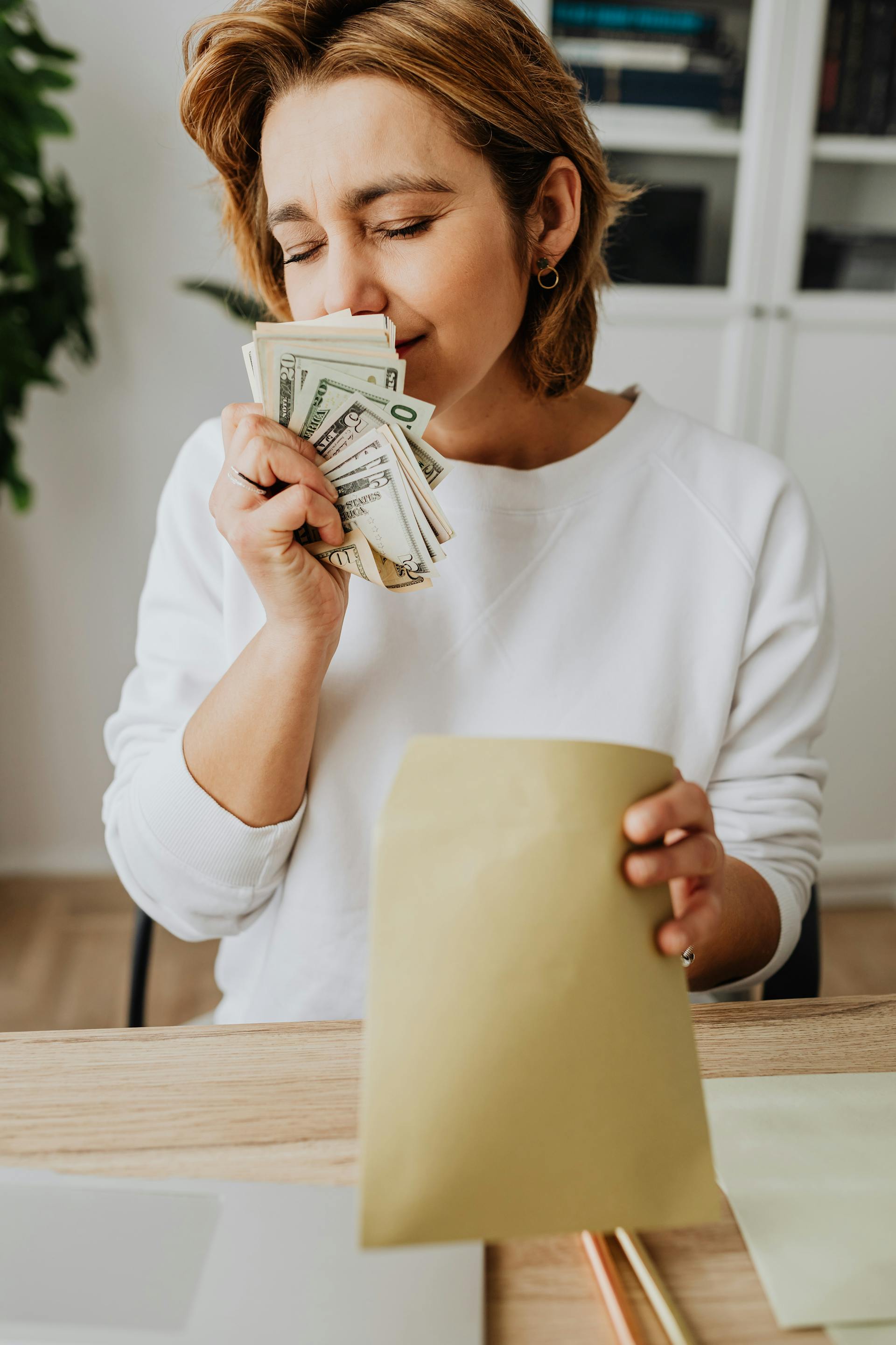 Une femme sent de l'argent les yeux fermés | Source : Pexels