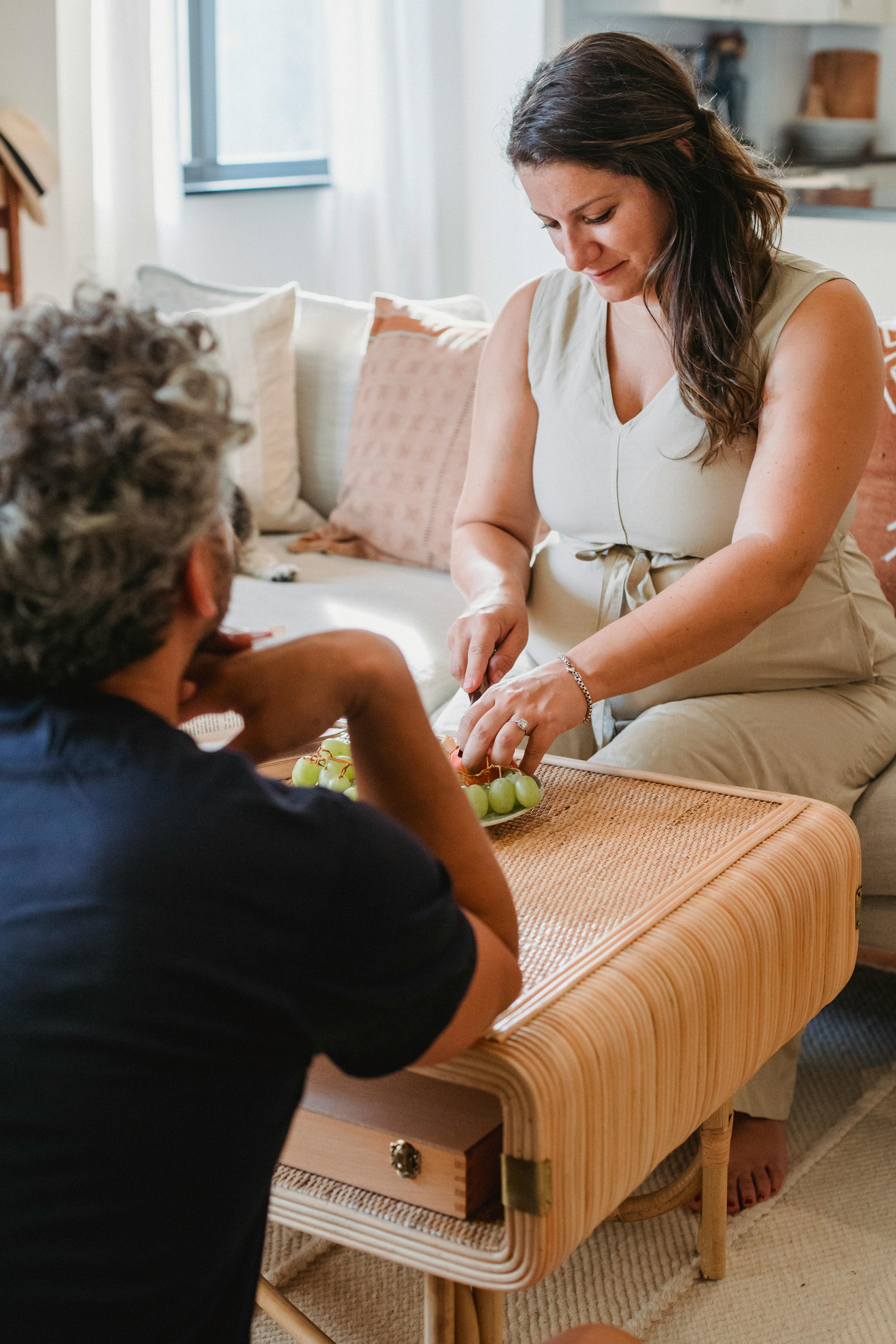 Un homme et une femme assis en silence pendant que la femme coupe des raisins | Source : Pexels