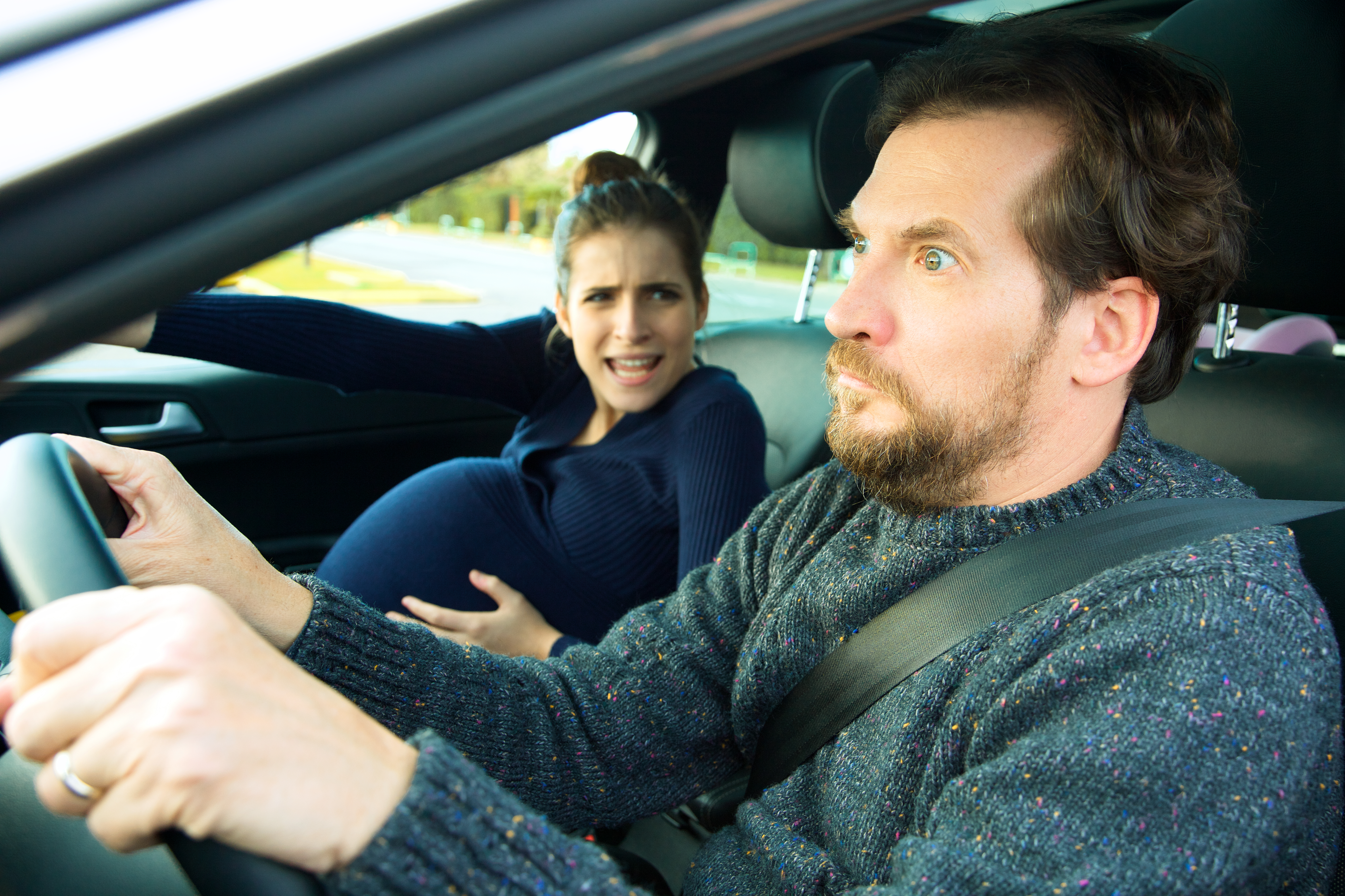 Un homme qui a l'air terrifié alors qu'il conduit avec une femme enceinte en train d'accoucher | Source : Shutterstock