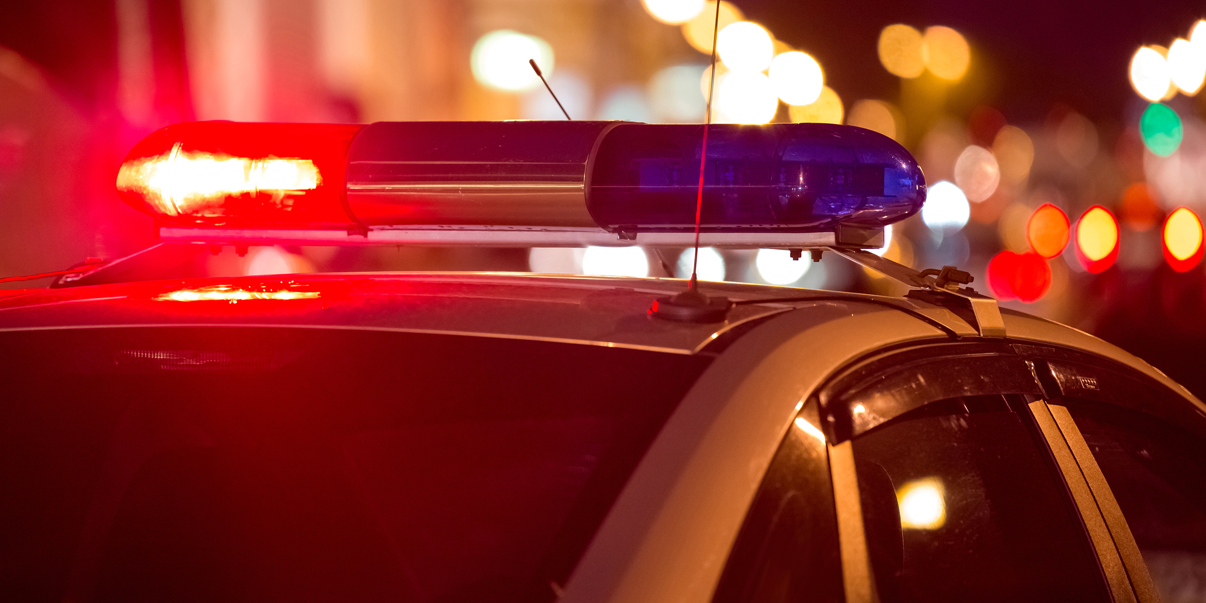 Une voiture de police avec des lumières rouges et bleues clignotantes la nuit | Source : Shutterstock