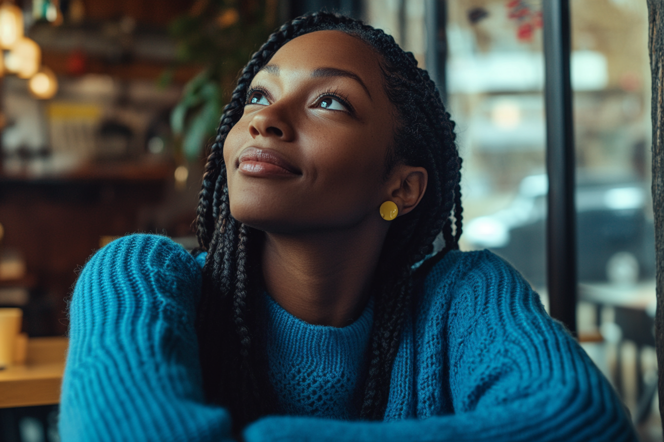 Une femme regarde en l'air alors qu'elle est assise à une table dans un café | Source : Midjourney