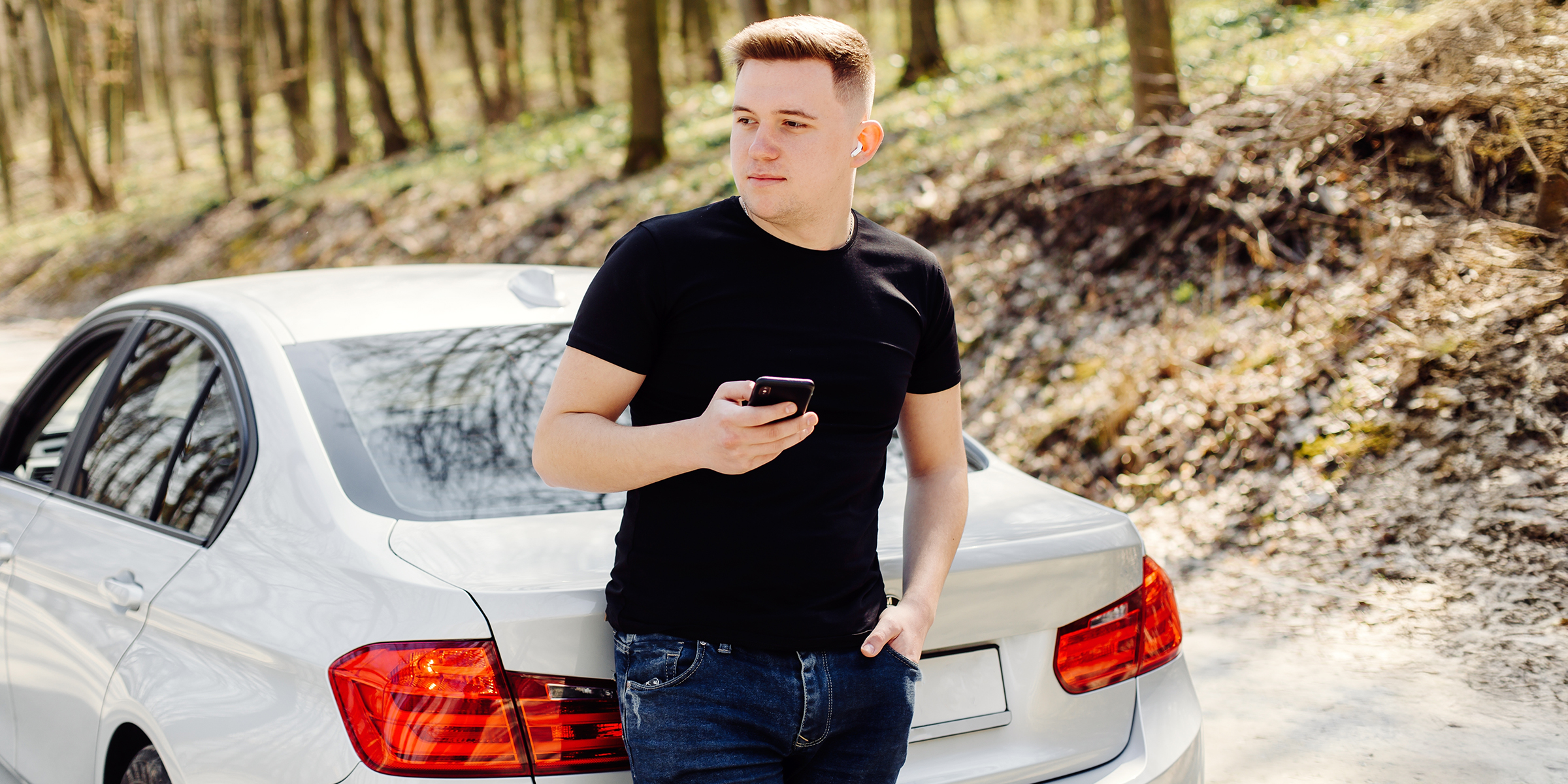 Un homme debout près d'une voiture et tenant un téléphone | Source : Shutterstock