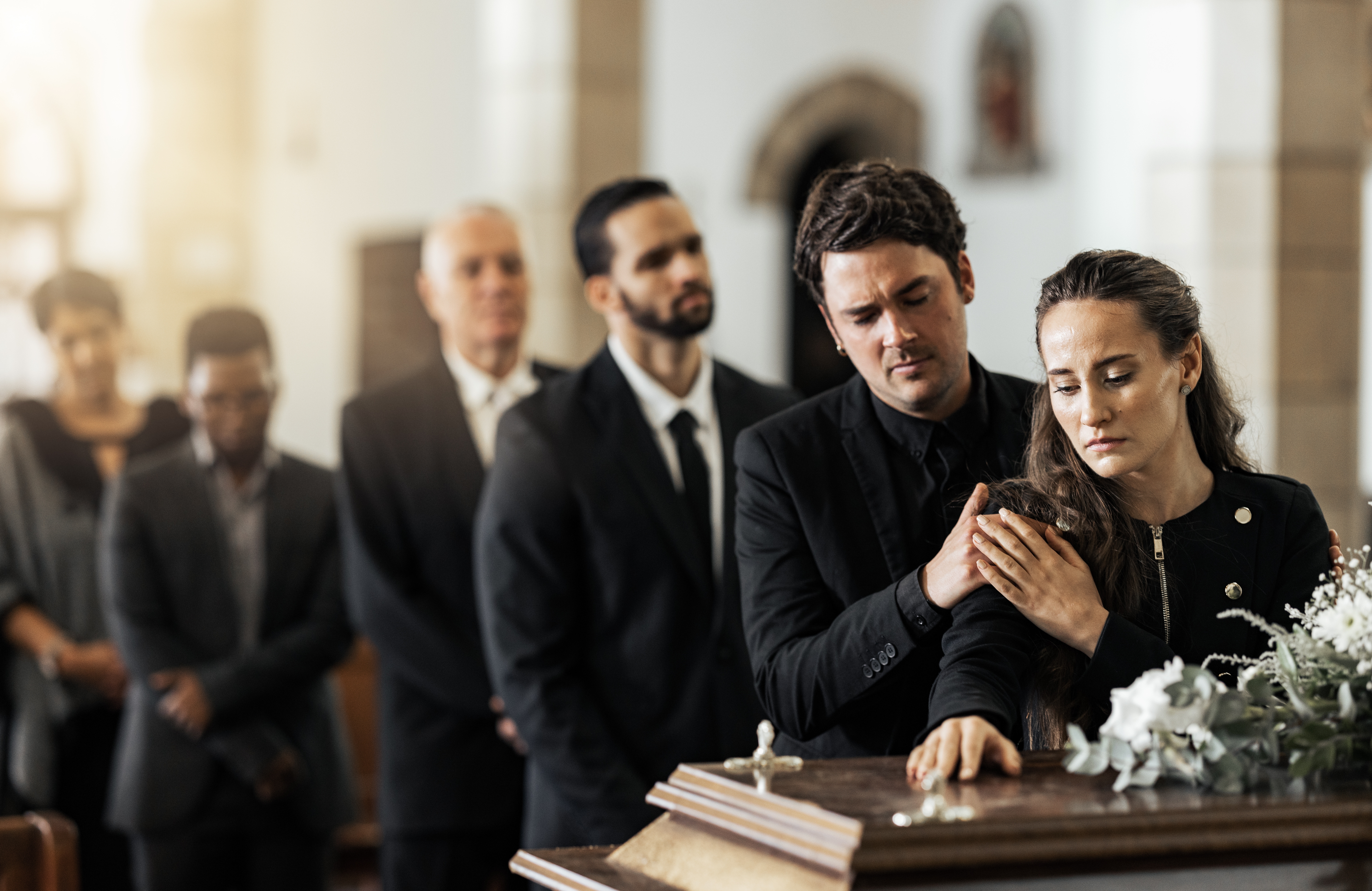 Des personnes se tiennent près d'un cercueil | Source : Shutterstock