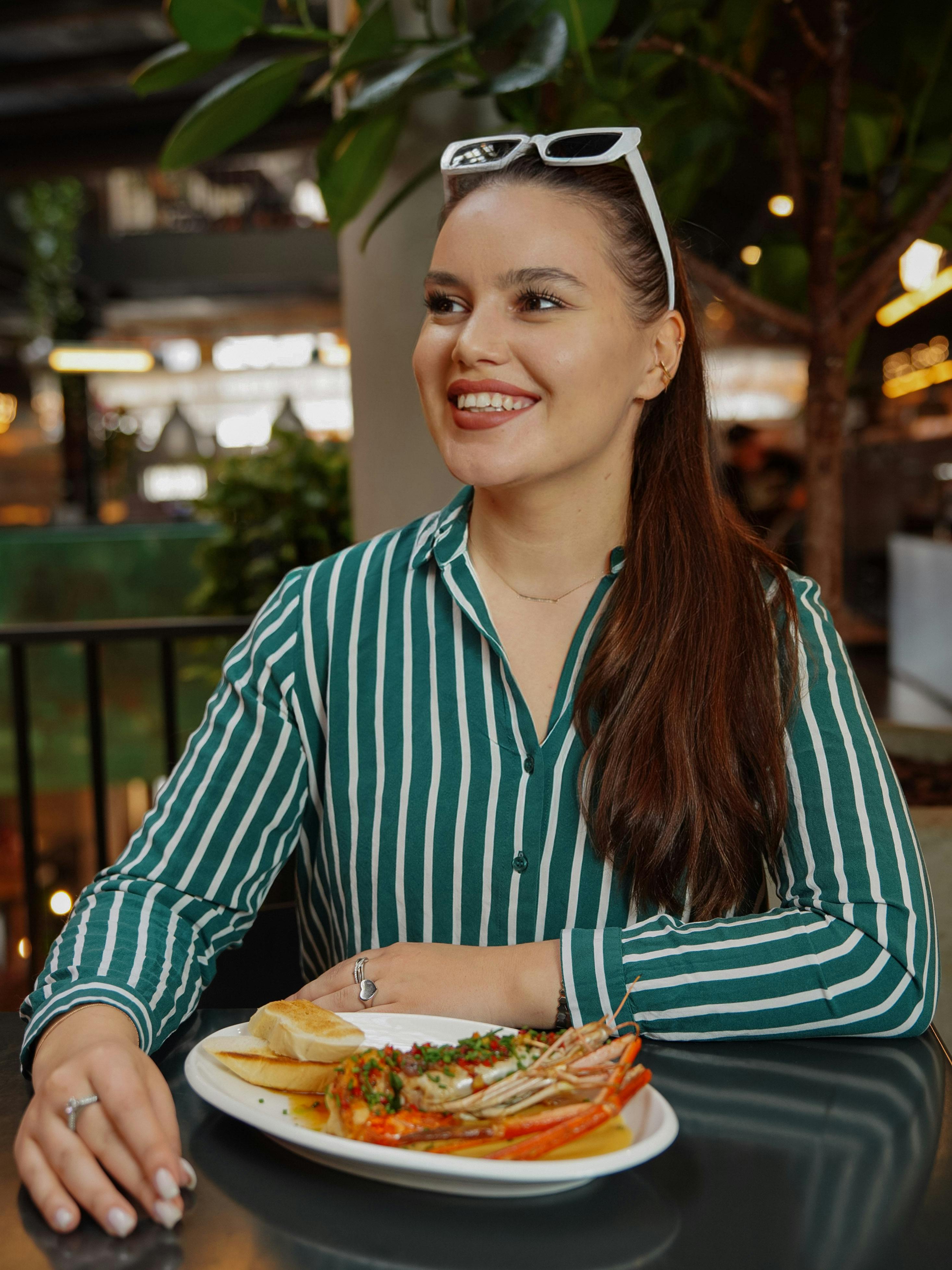 Une jeune femme heureuse mangeant un dîner de homard | Source : Pexels