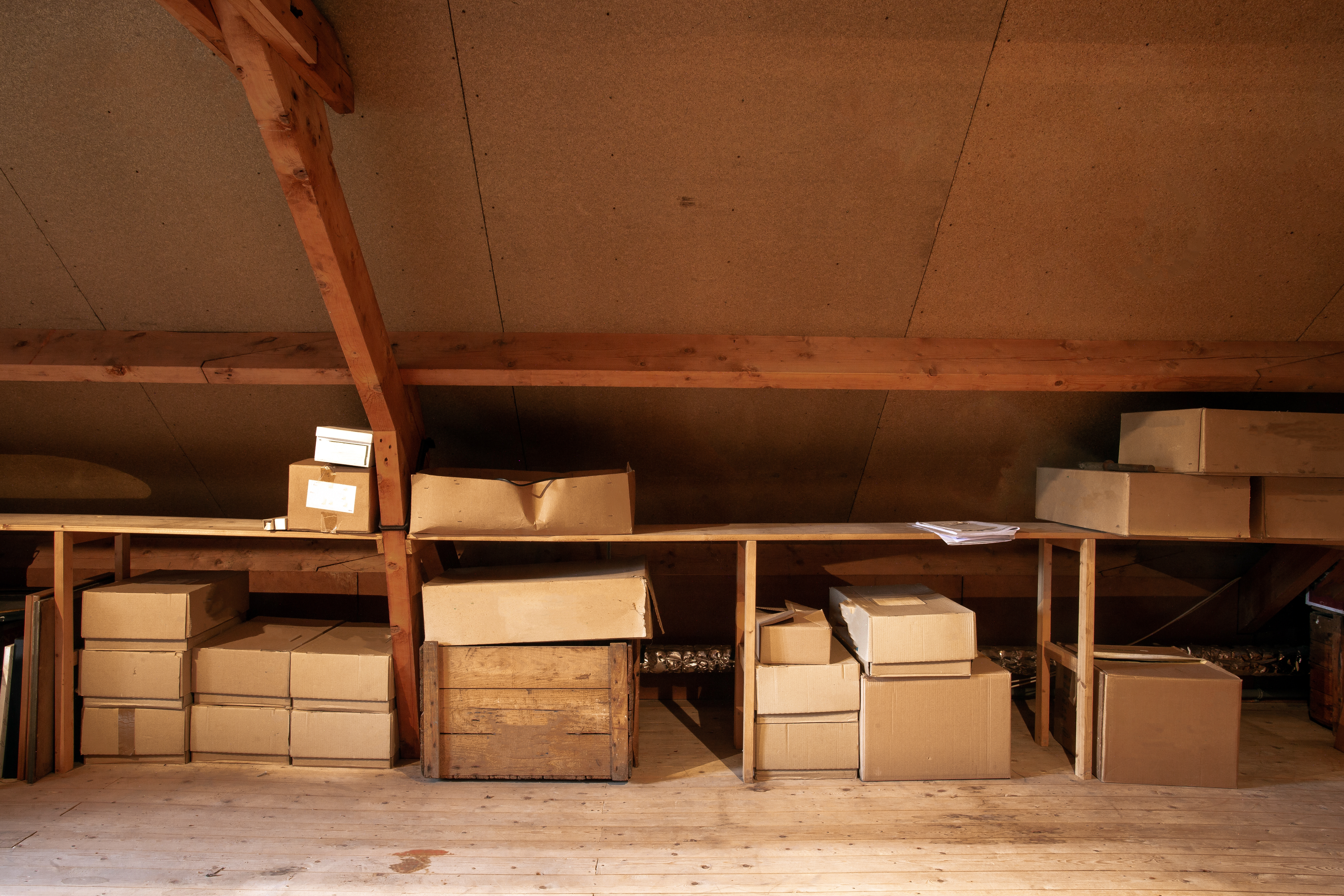Un vieil intérieur de grenier en bois avec de vieilles boîtes en carton pour le rangement | Source : Shutterstock