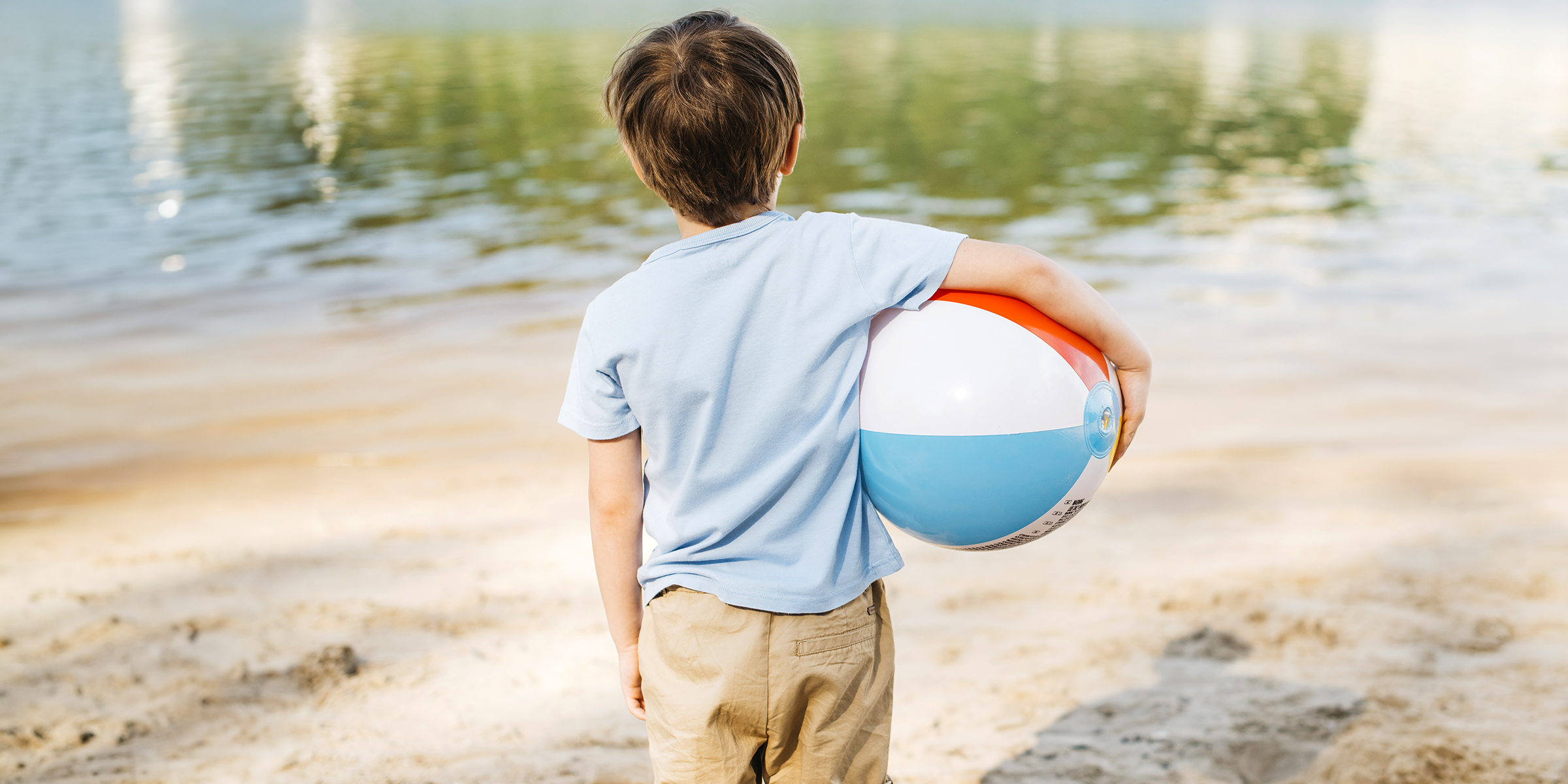 Un petit garçon tenant un ballon sur la plage | Source : Freepik