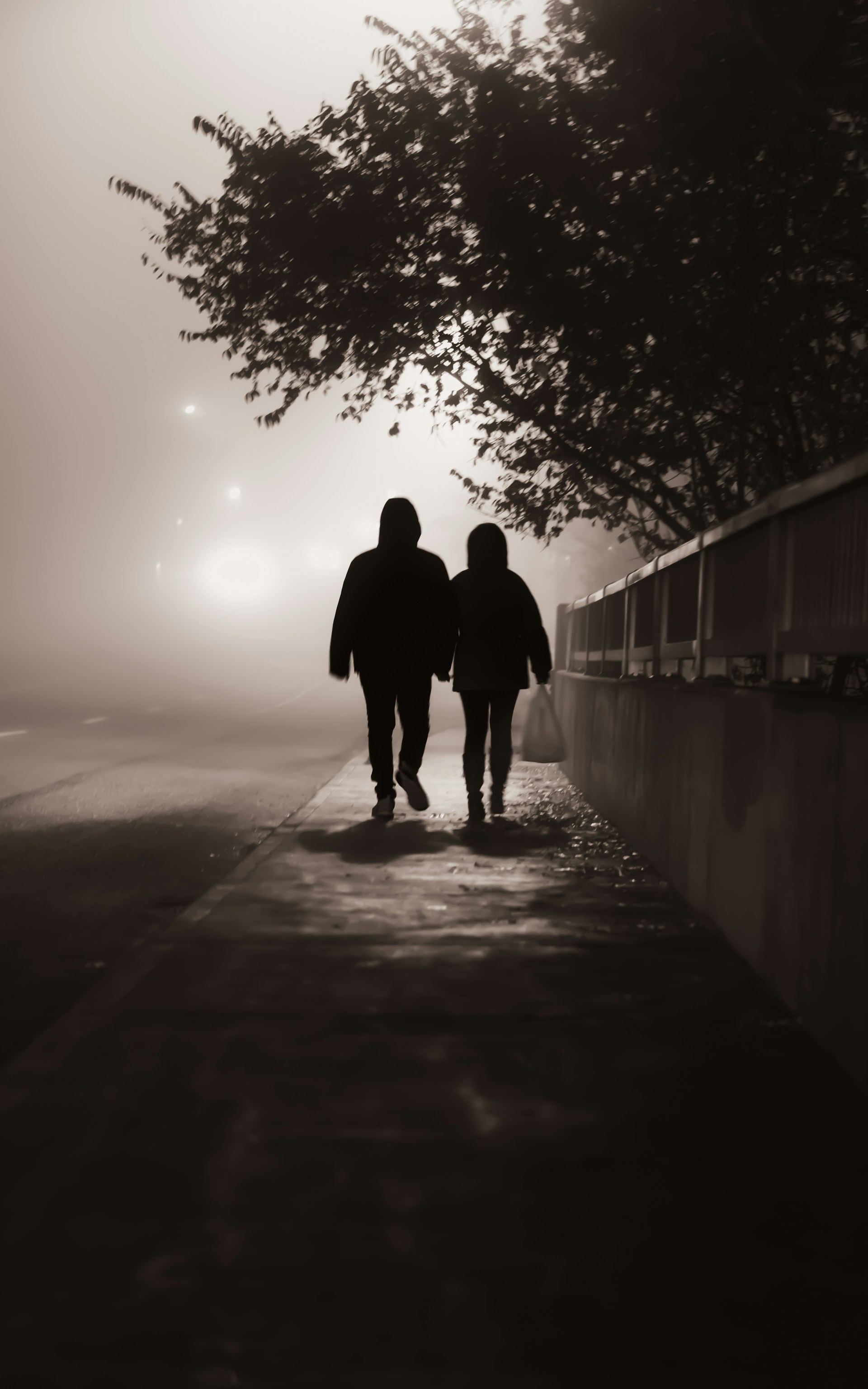 Un couple marchant sur le trottoir par une soirée brumeuse | Source : Unsplash