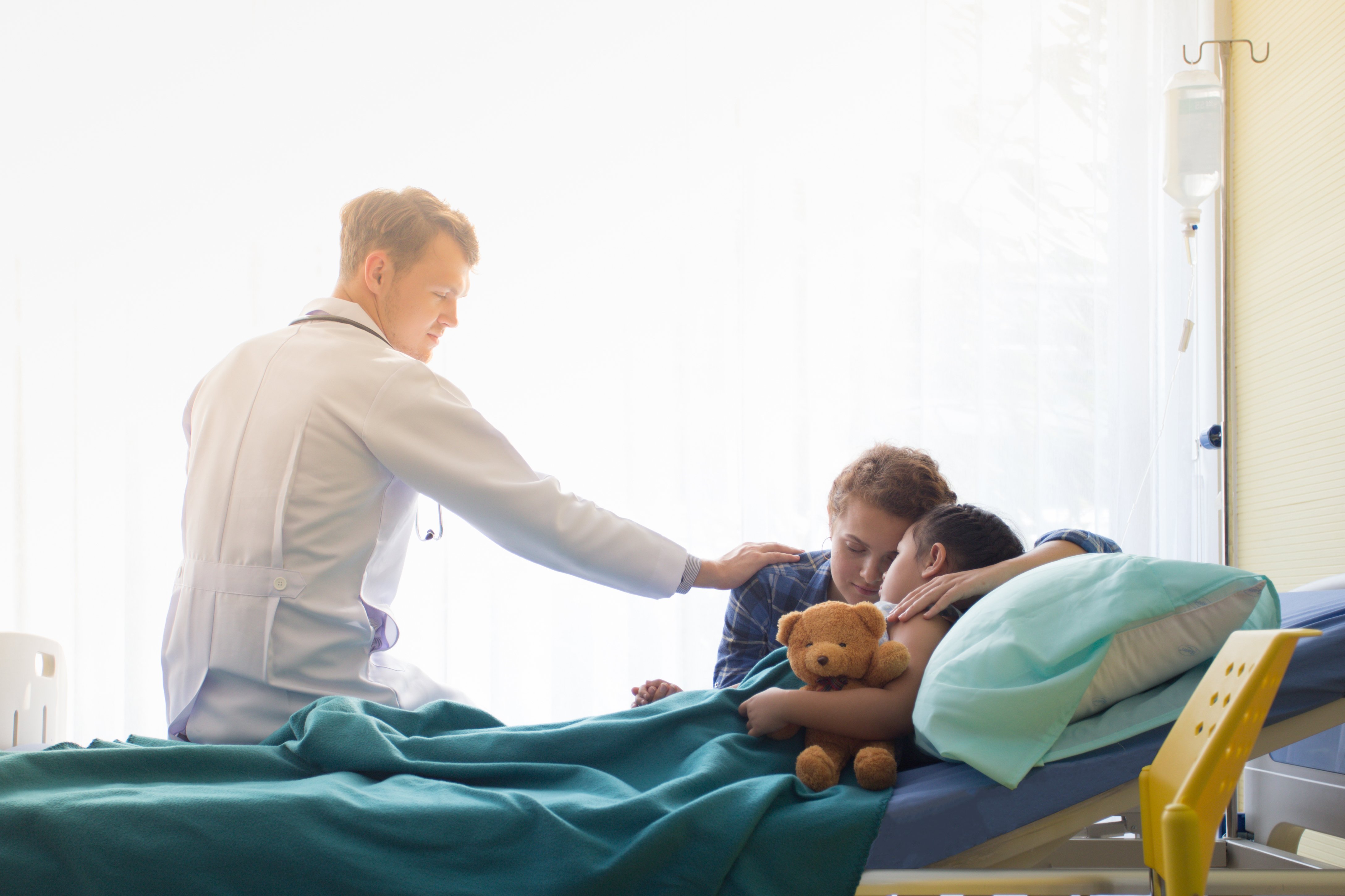Un médecin qui rassure une mère et son enfant sur un lit d'hôpital | Photo : Shutterstock