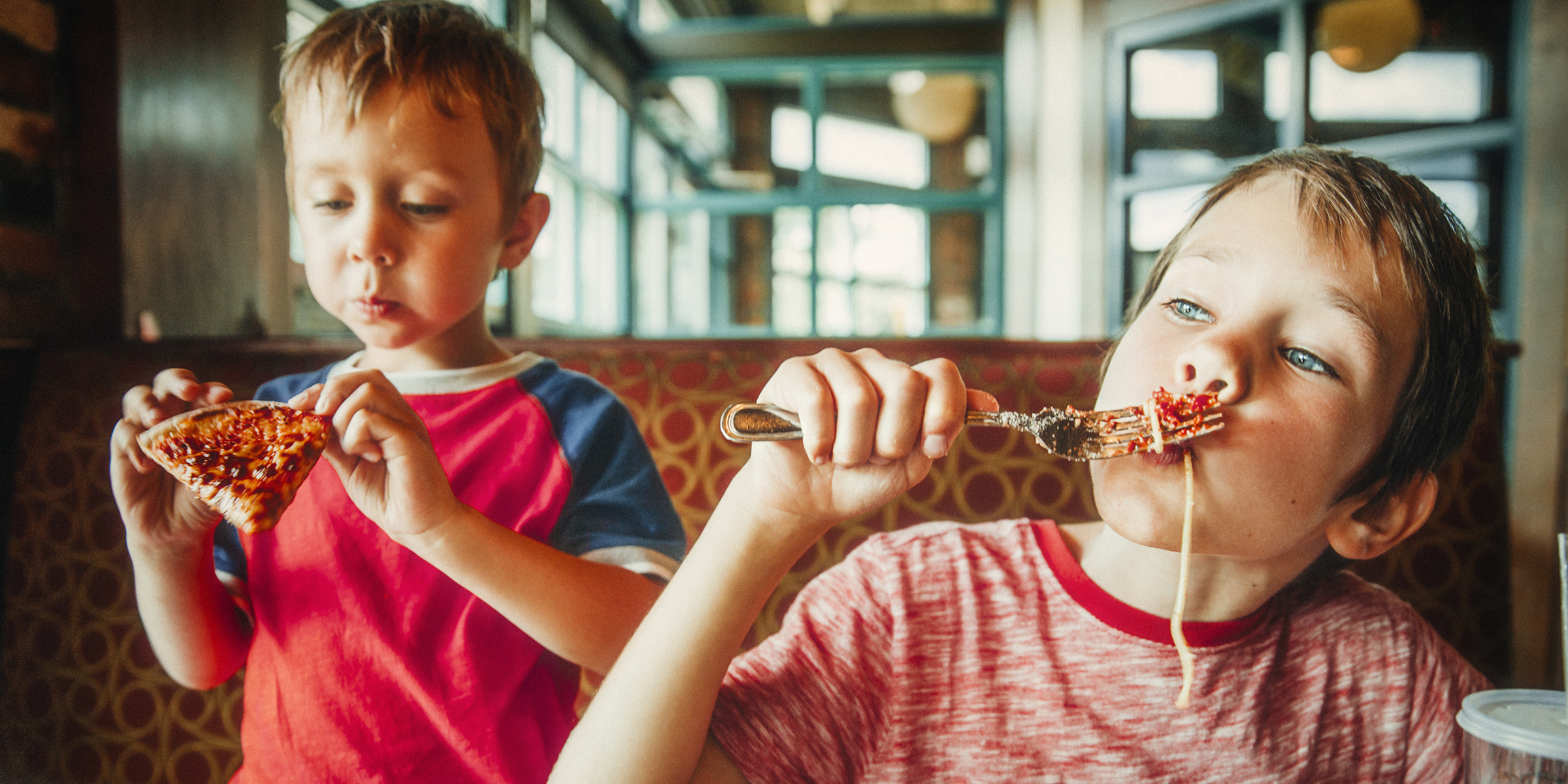 Deux enfants dégustant une pizza | Source : Shutterstock