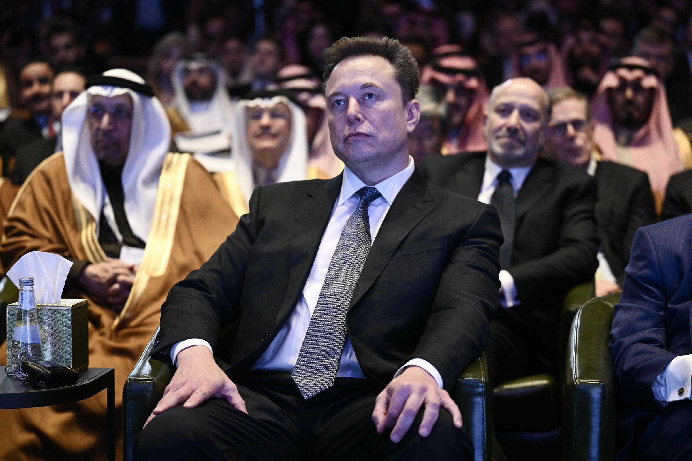 Elon Musk observe le président américain Donald Trump s'exprimer lors du Forum d'investissement américano-saoudien au John F. Kennedy Center for the Performing Arts à Washington, DC, le 19 novembre 2025. | Source : Getty Images