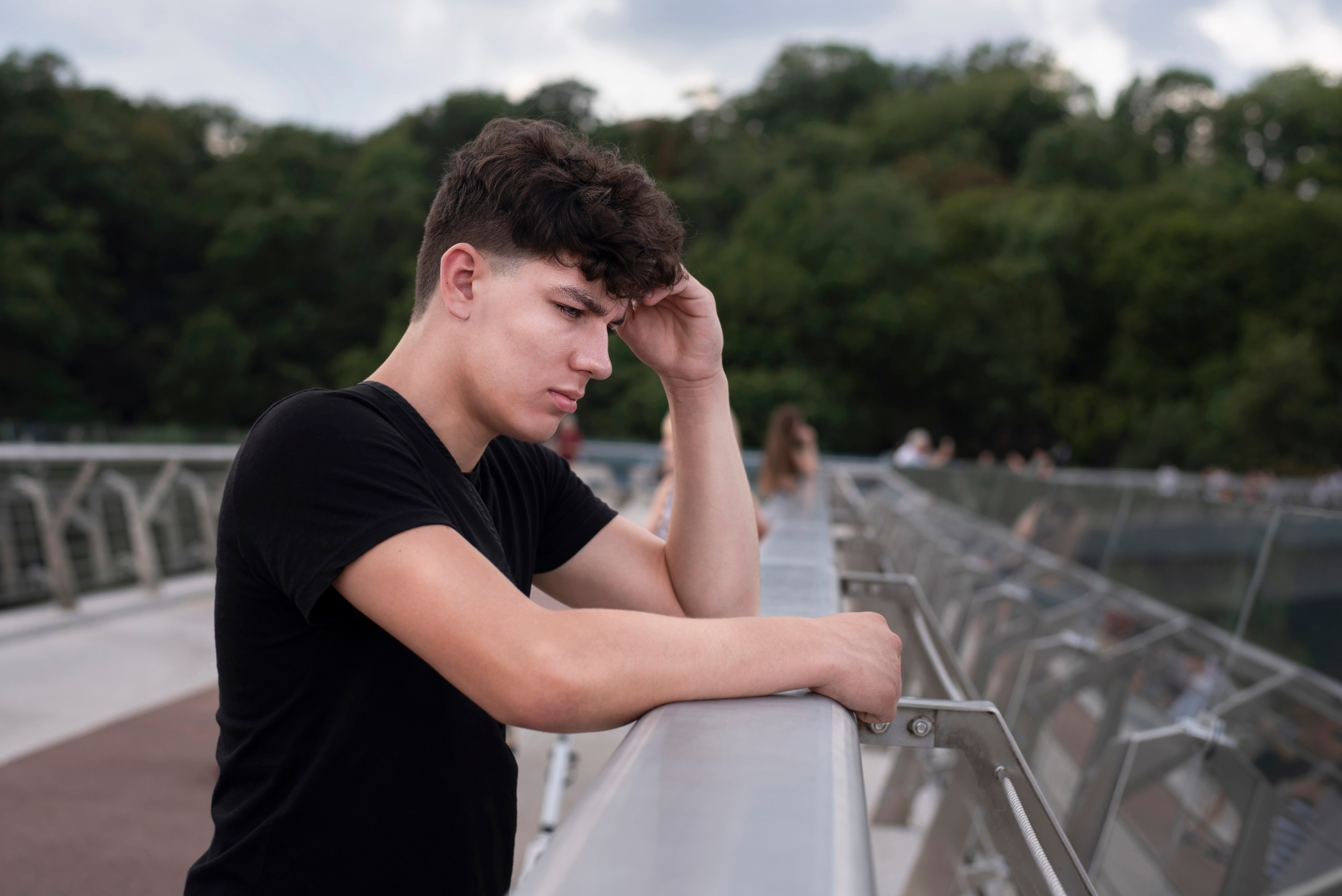 Un adolescent qui a l'air triste alors qu'il se tient près d'un pont | Source : Shutterstock