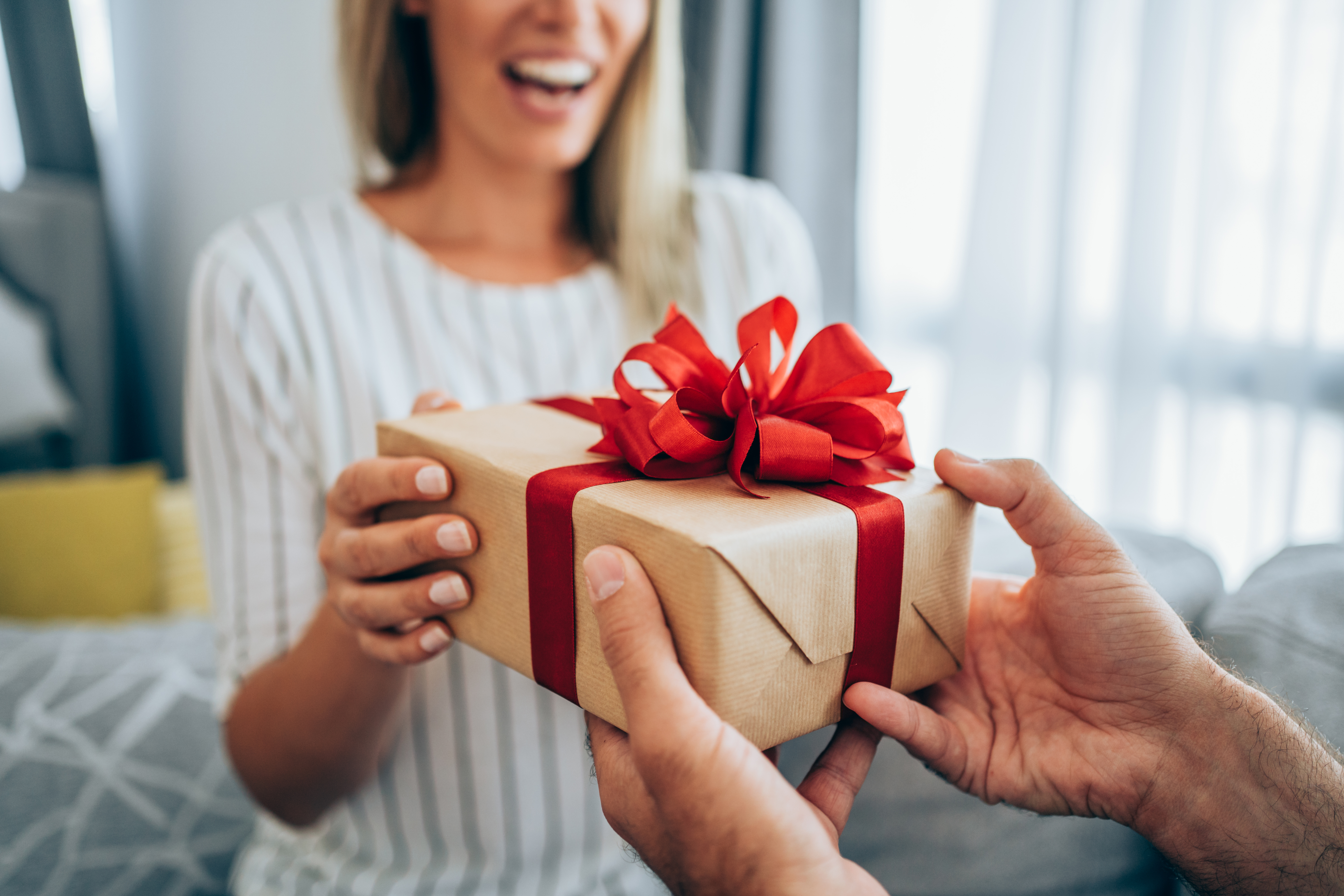 Une femme heureuse recevant un cadeau de la part d'un homme | Source : Getty Images