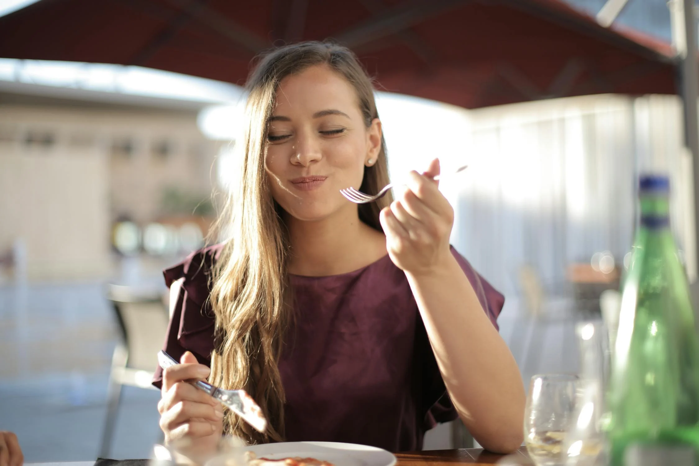 Une femme souriante mangeant dans un café | Source : Pexels