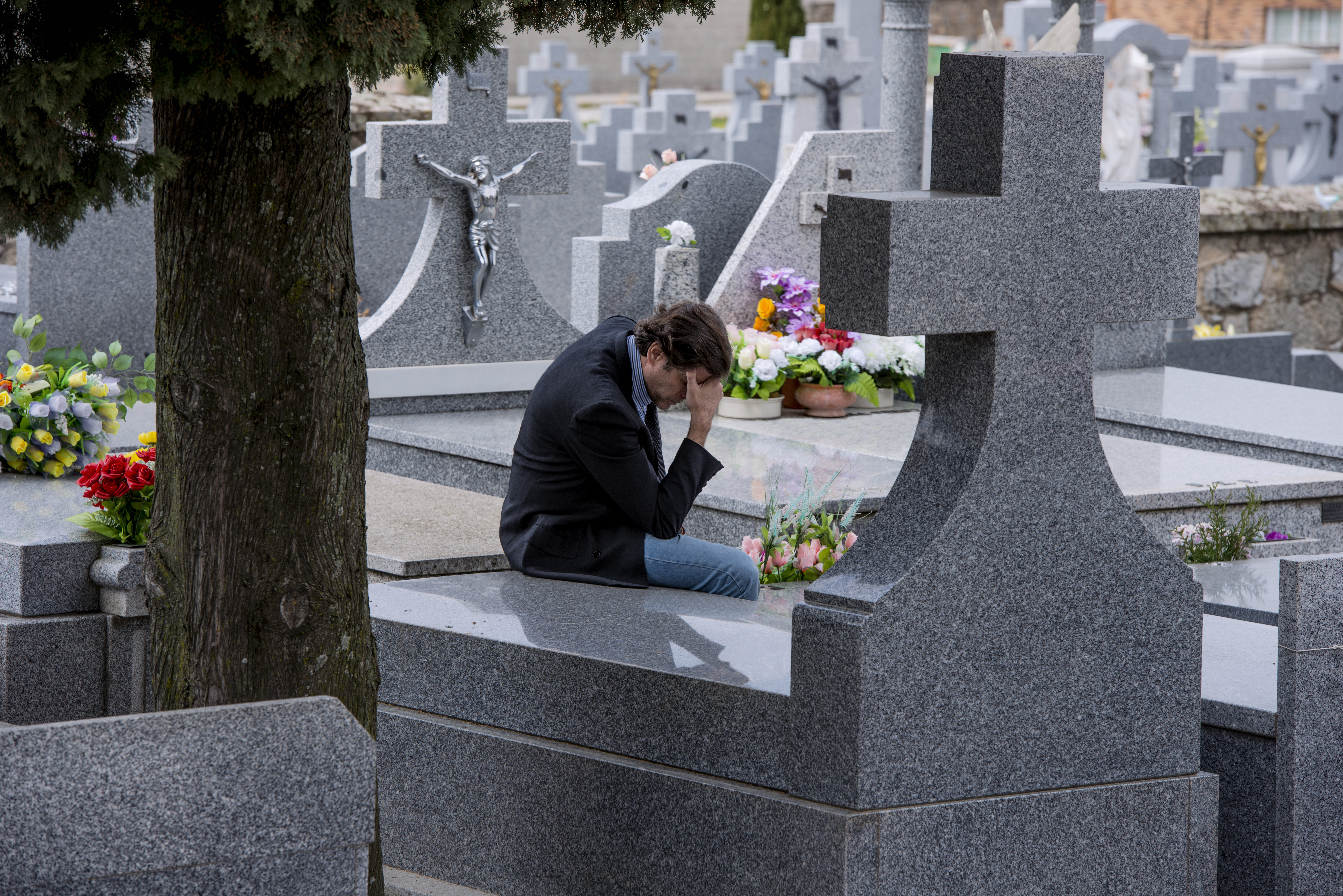 Un homme assis devant une tombe | Source : Shutterstock