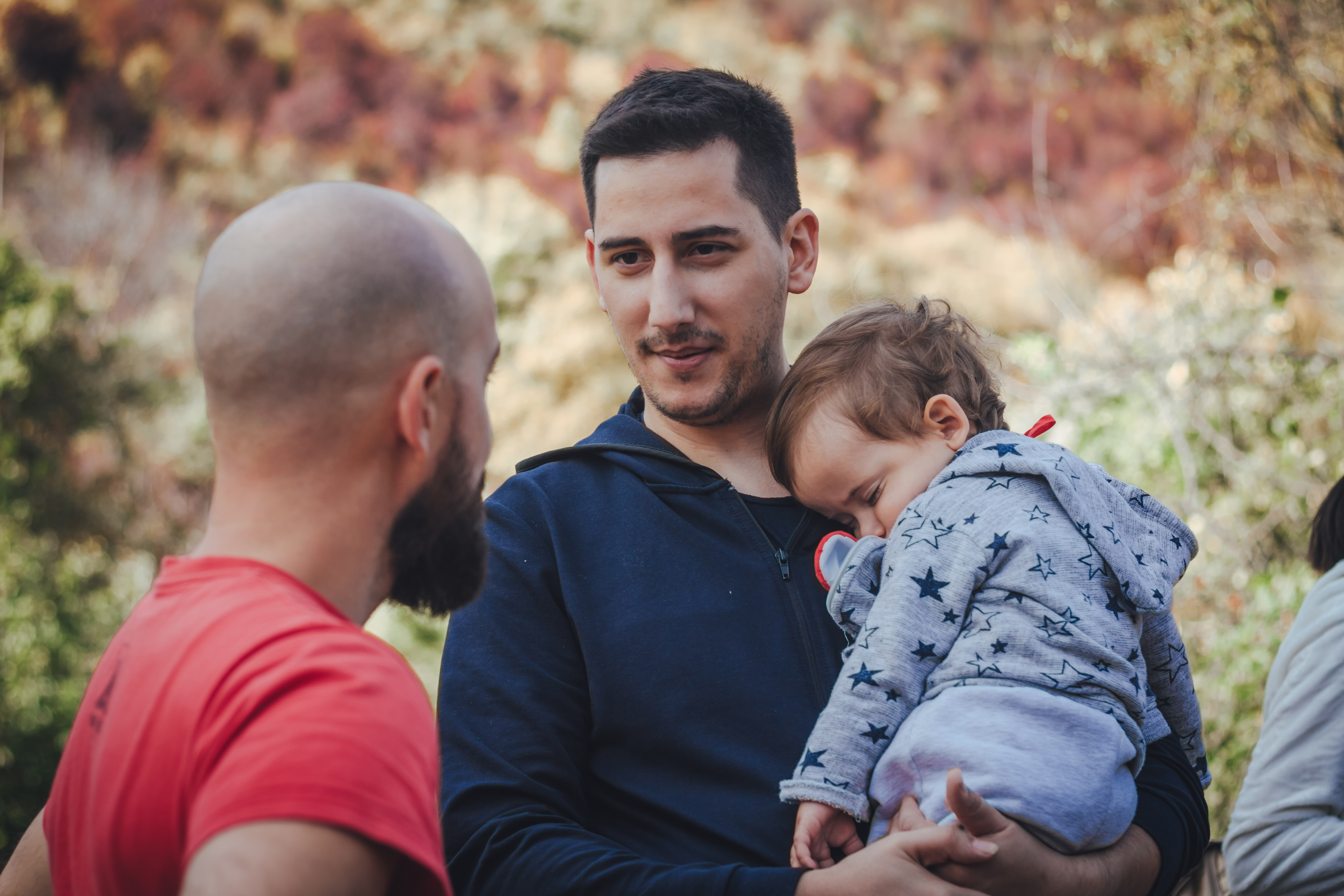Deux hommes discutent et l'un d'eux tient un bébé | Source : Shutterstock