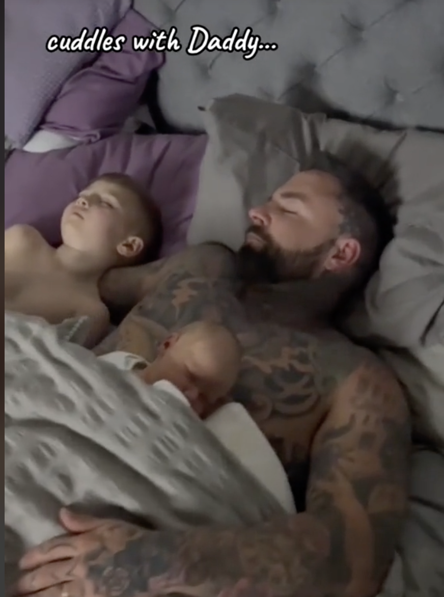 Roman est photographié en train de dormir avec son père, Tom, et son jeune frère ou sa jeune sœur. | Source : tiktok.com/@tom_leeds