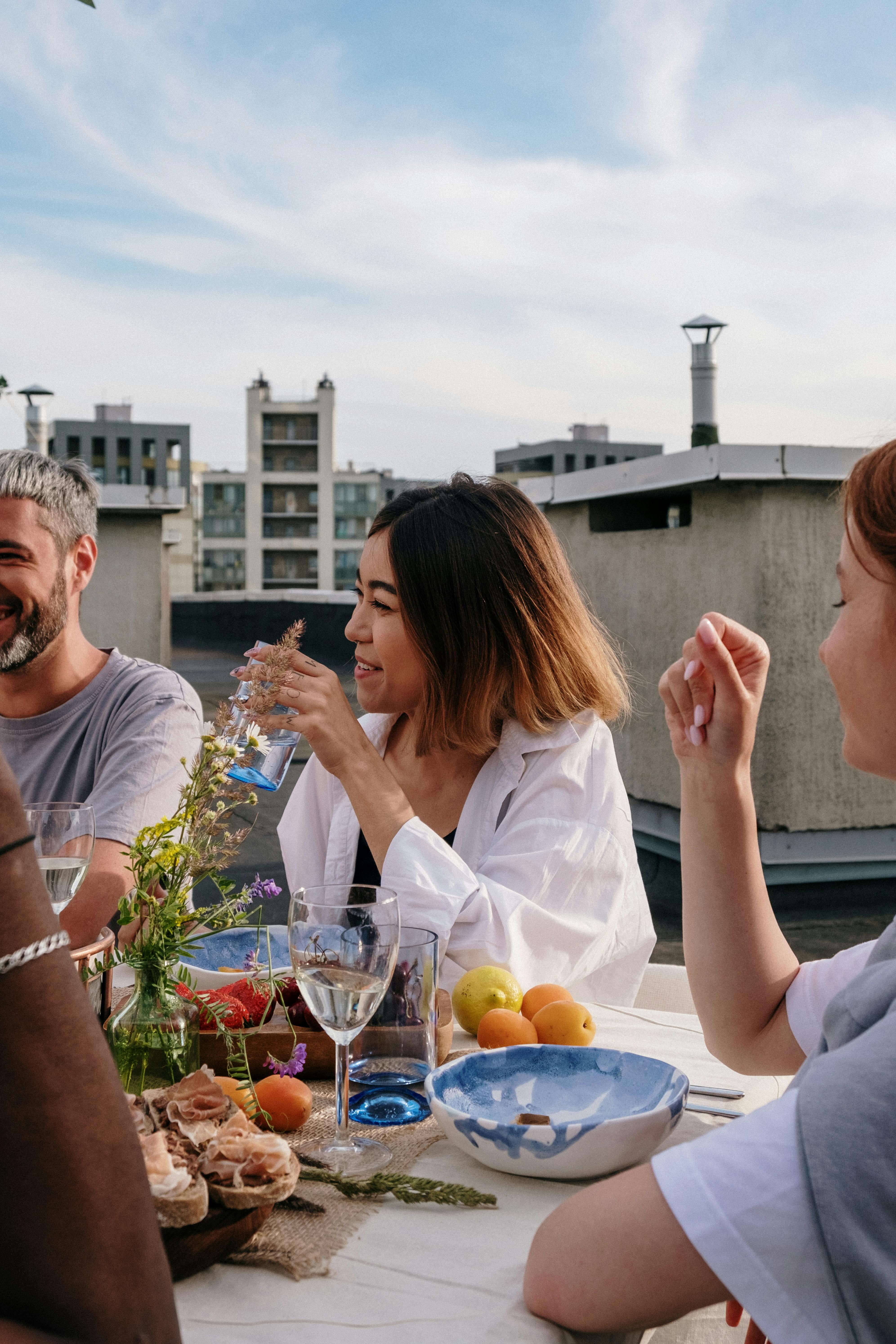 People talking and laughing around a table full of food | Source: Pexels