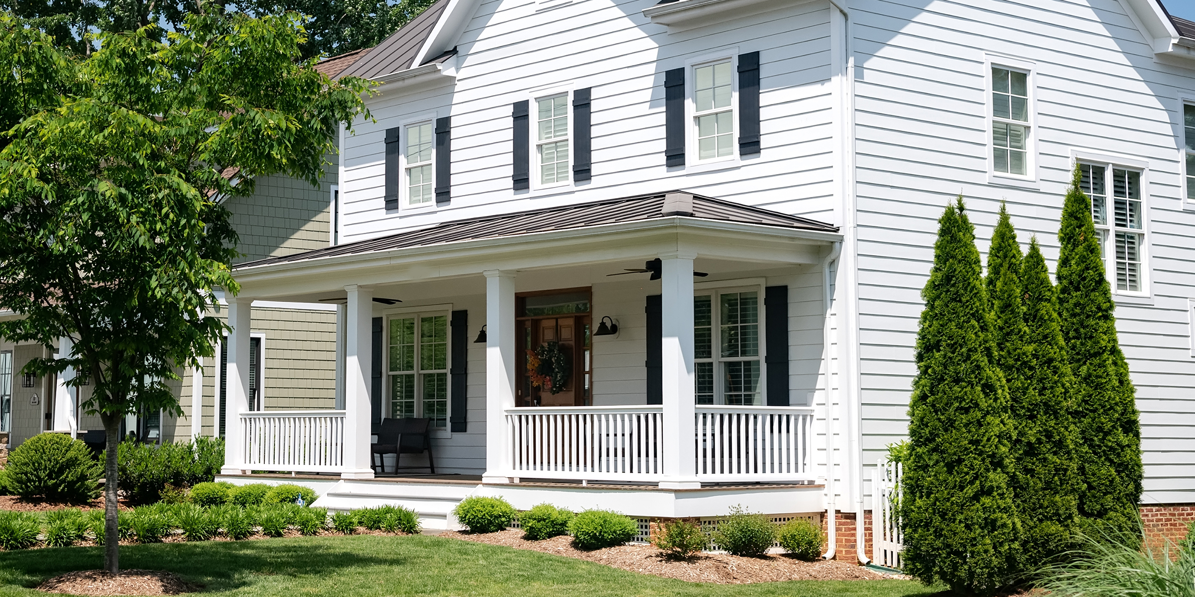 Une maison blanche classique avec un porche enveloppant | Source : Shutterstock