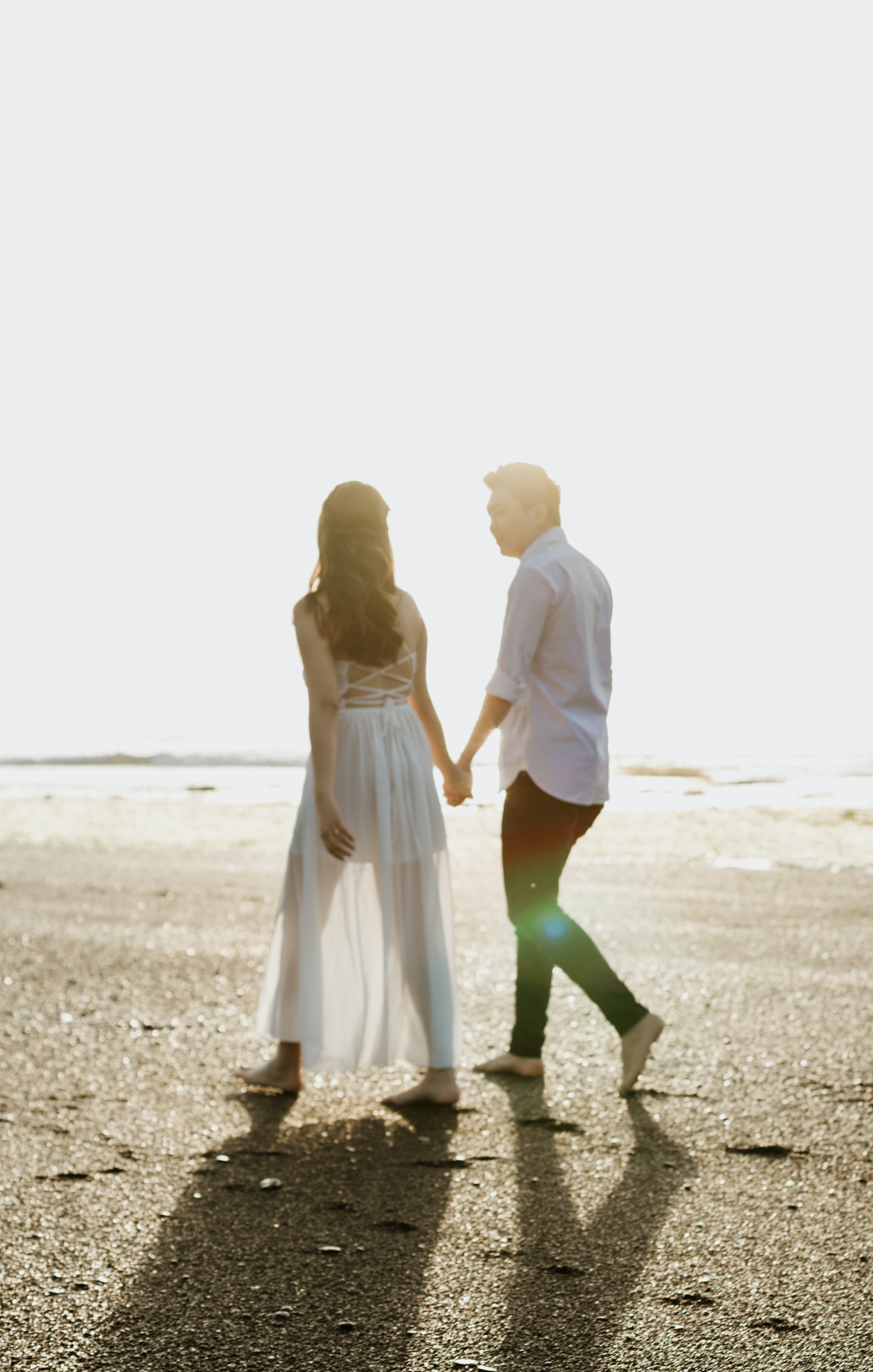 Un couple se tenant par la main tout en marchant sur la plage | Source : Pexels