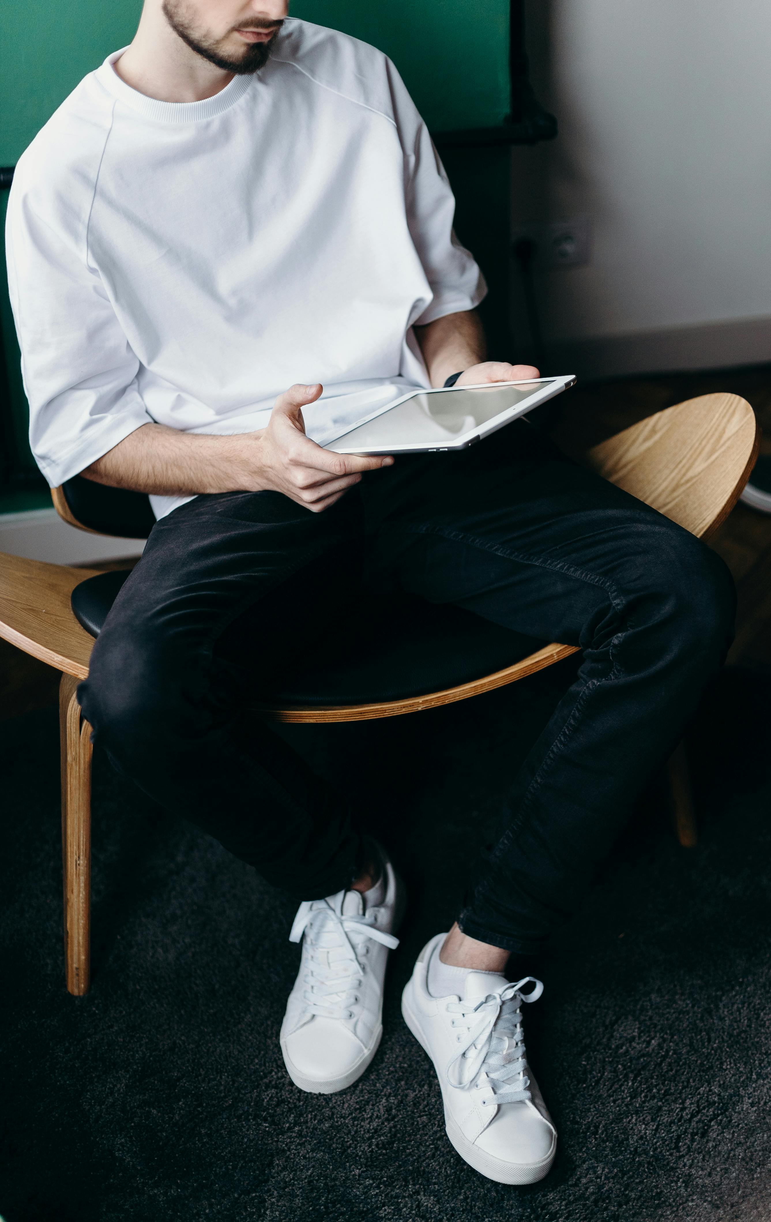 Homme en chemise blanche et pantalon noir utilisant une tablette | Source : Pexels