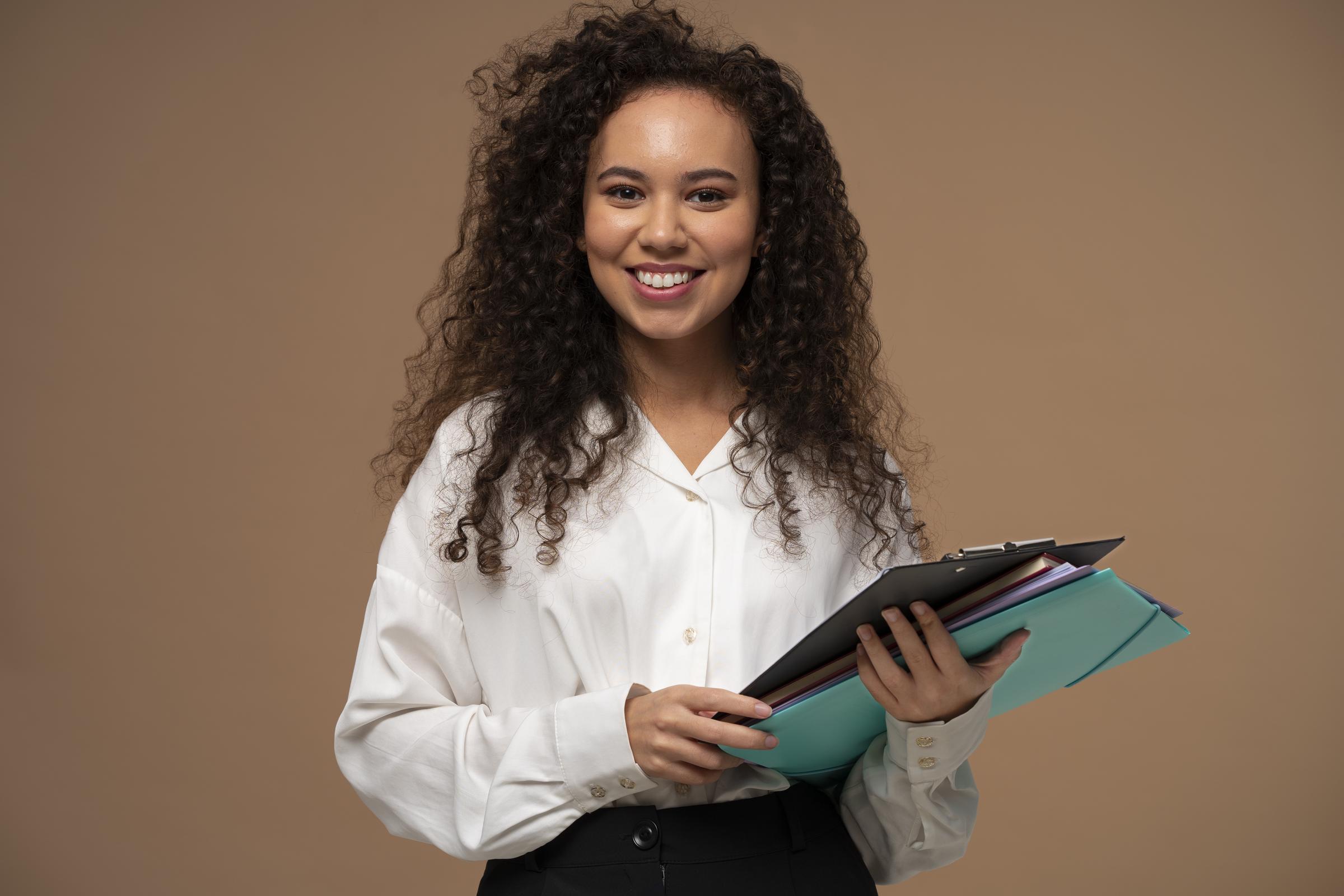 Une jeune femme tenant des documents administratifs | Source : Freepik