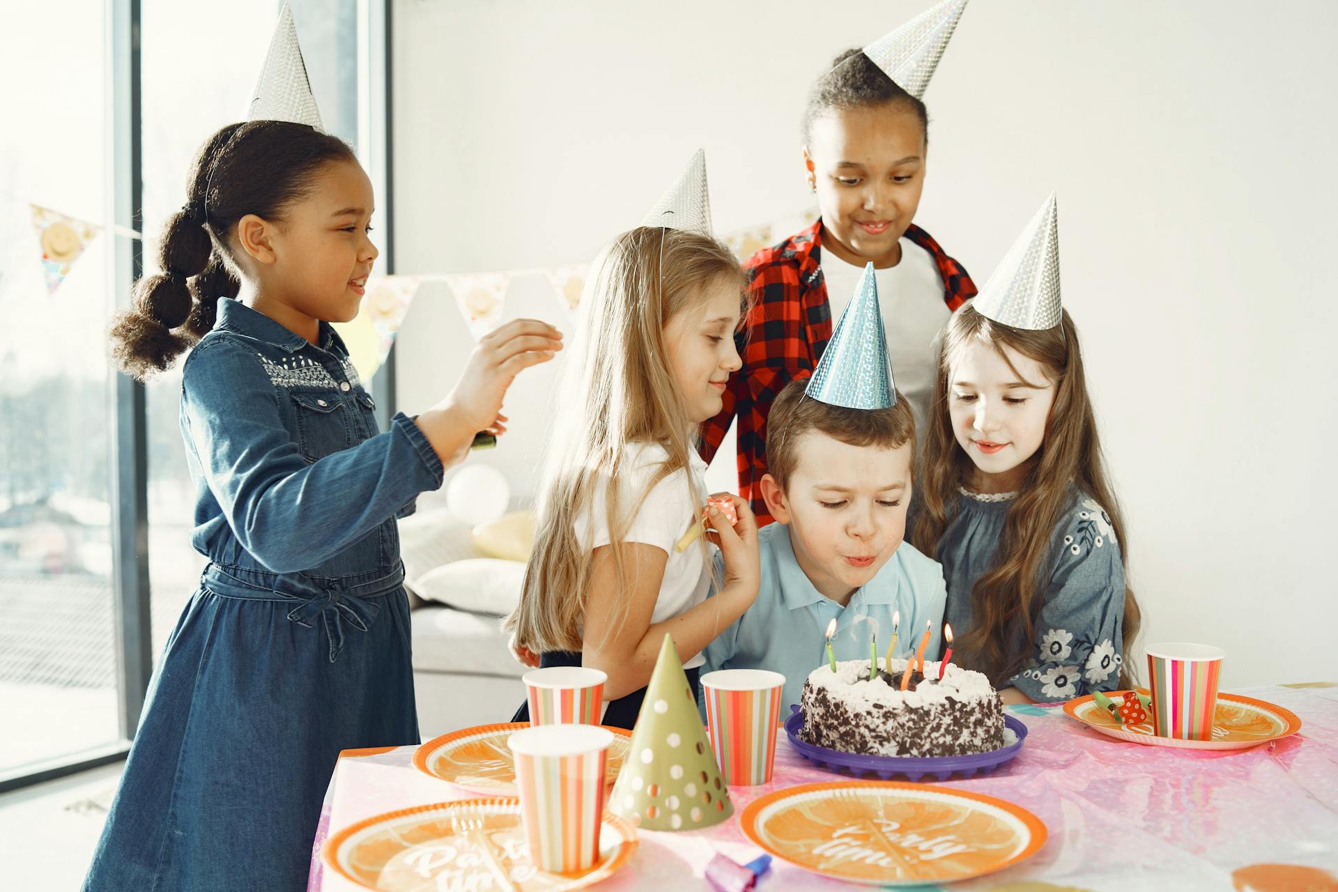 Un garçon souffle les bougies de son gâteau d'anniversaire tandis que des enfants ravis l'entourent | Source : Pexels