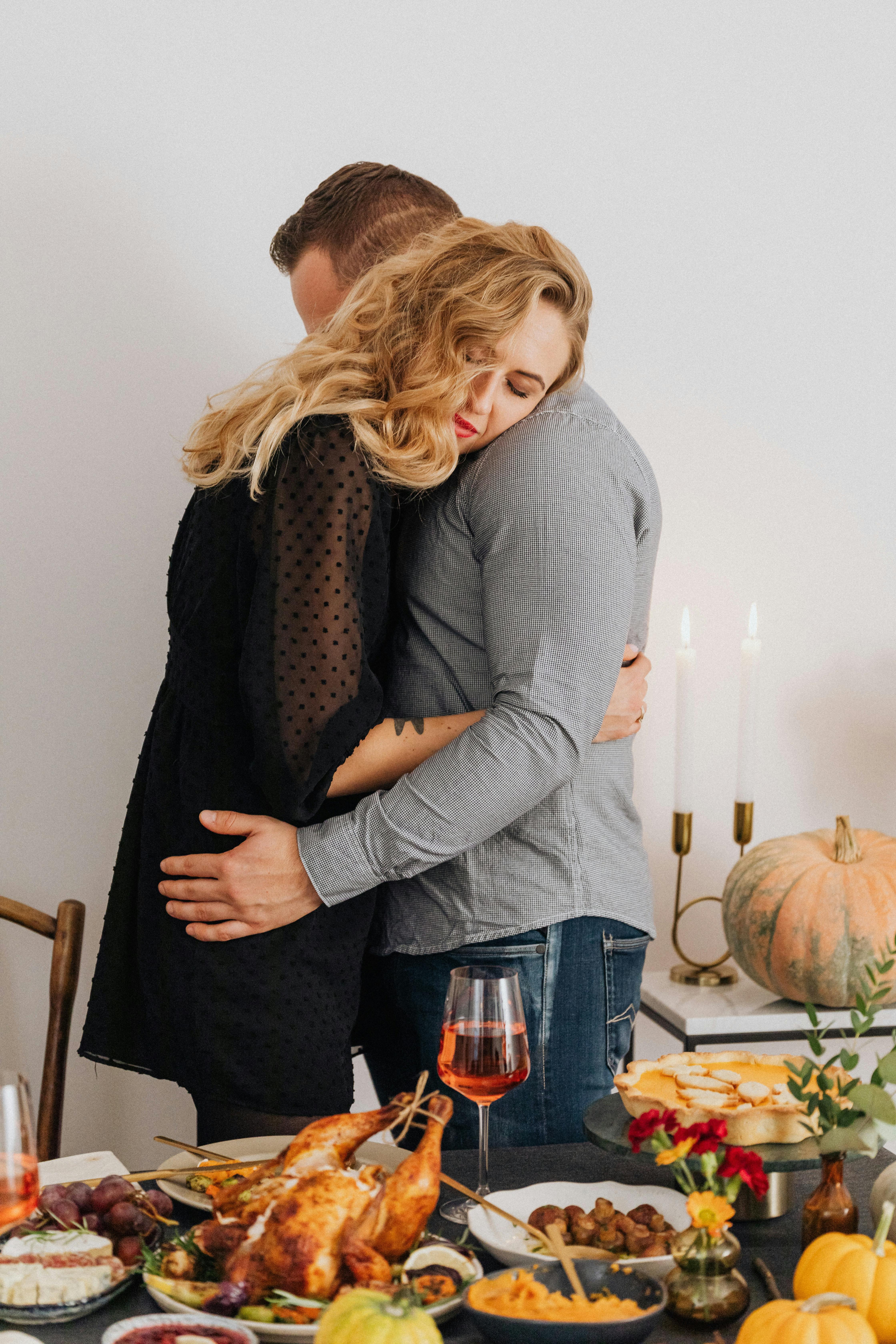 Un couple s'étreint près d'une table garnie de nourriture | Source : Pexels