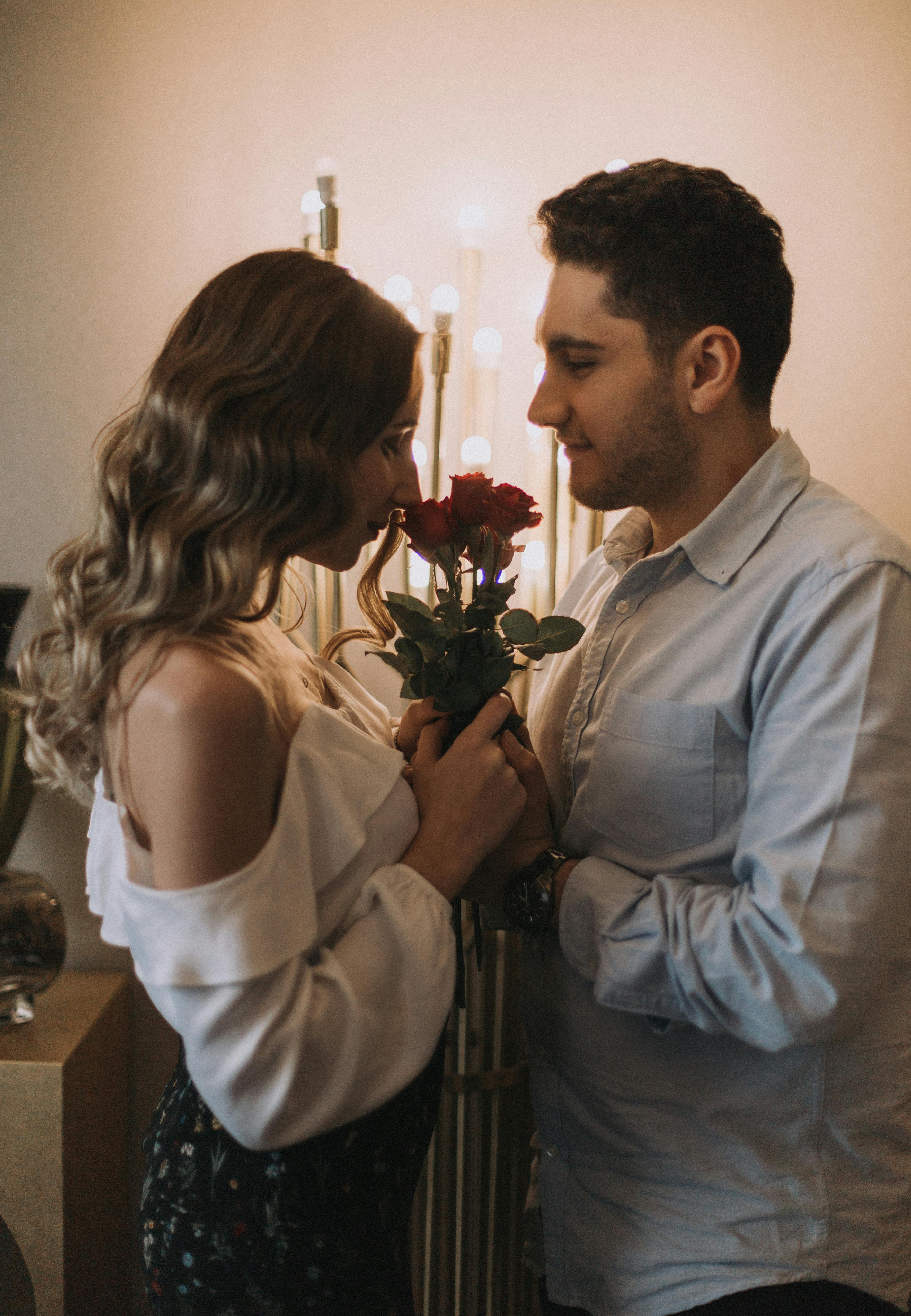 Un couple qui se regarde fixement avec un bouquet de roses entre eux | Source : Pexels