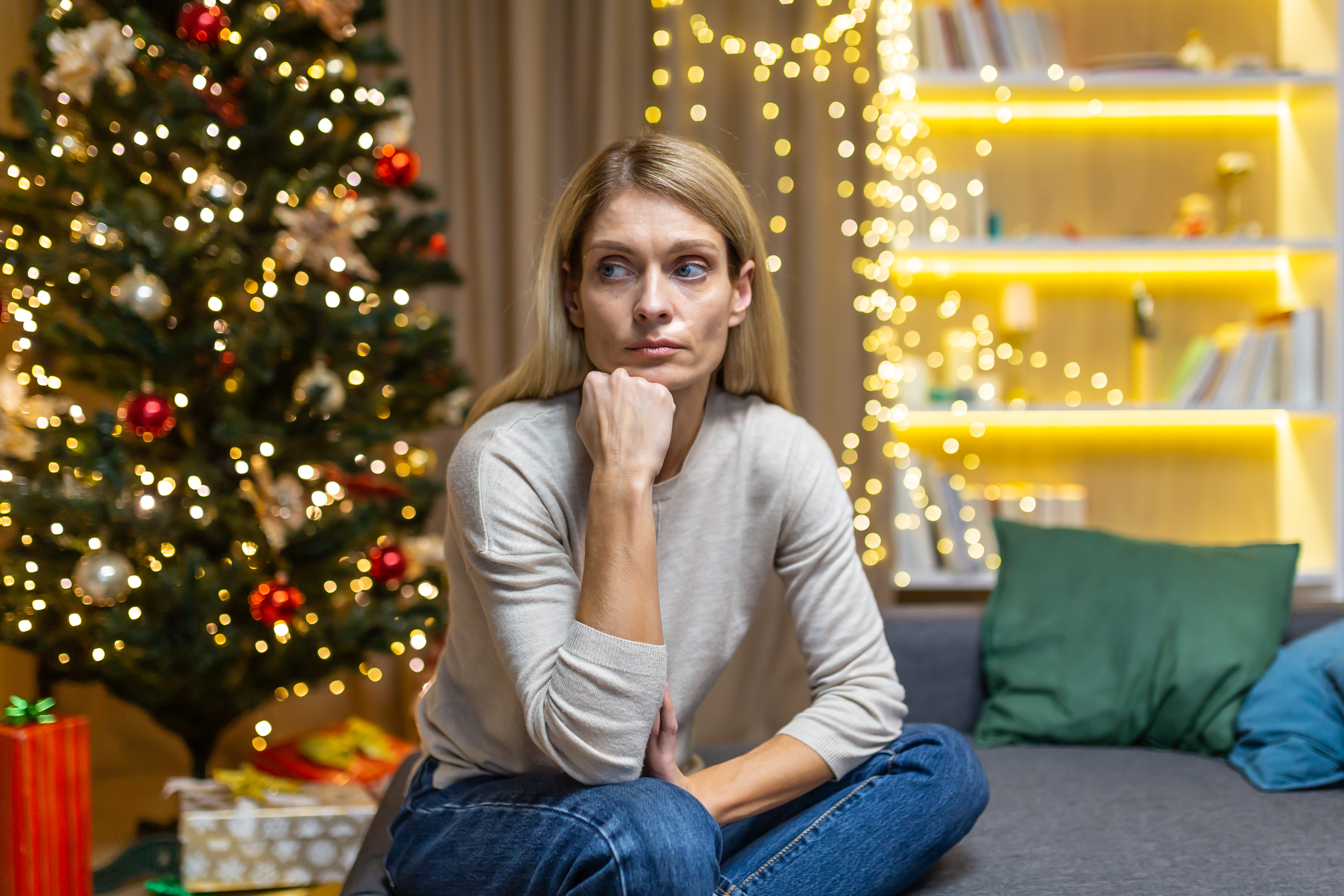 Une femme déprimée assise près d'un arbre de Noël à la maison | Source : Getty Images