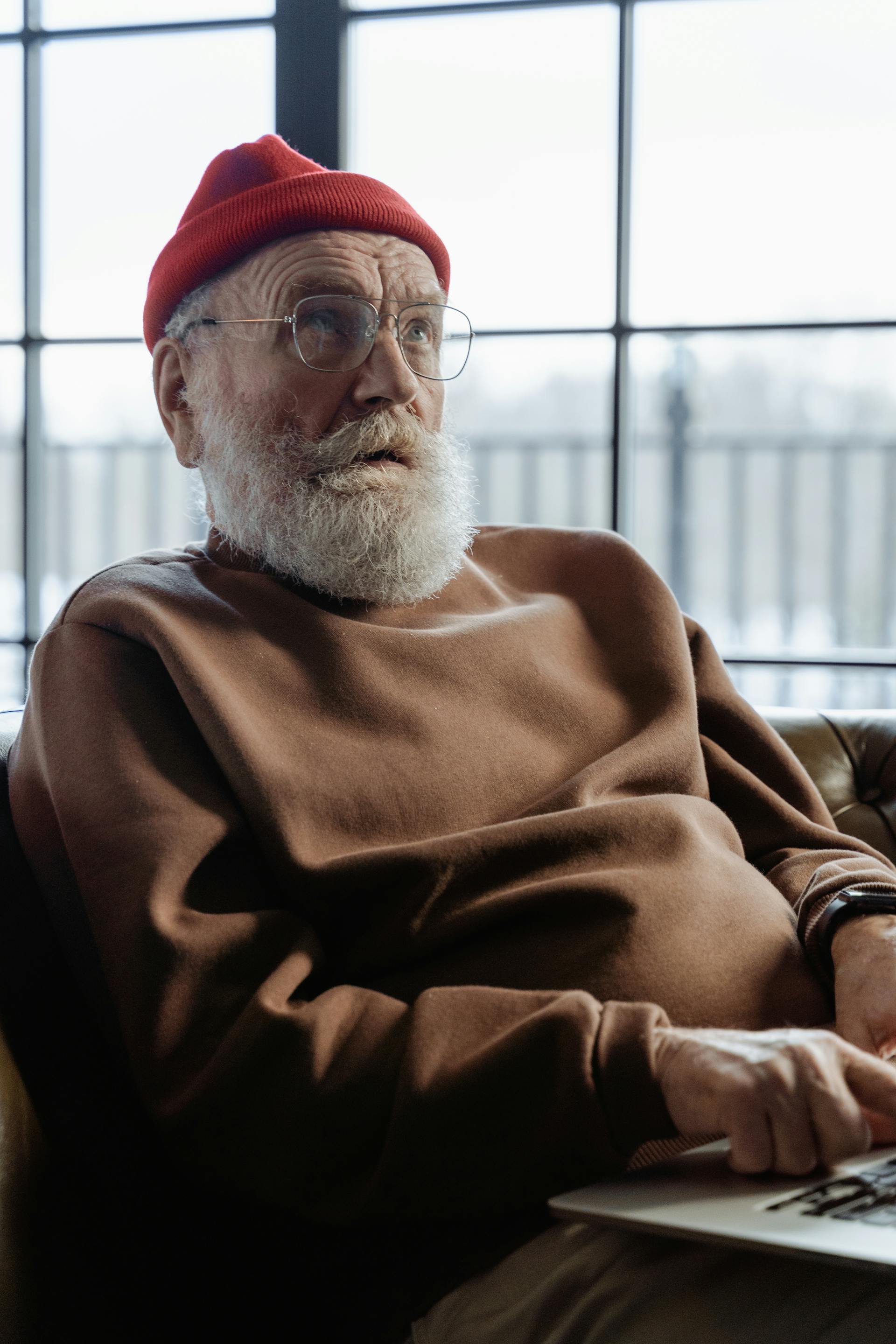 Un homme âgé avec un bonnet rouge assis sur une chaise et regardant quelqu'un | Source : Pexels